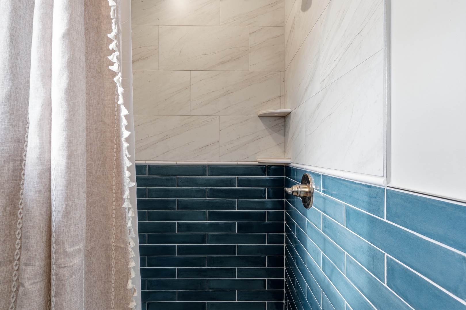 Walk-in shower with marble and blue subway tile