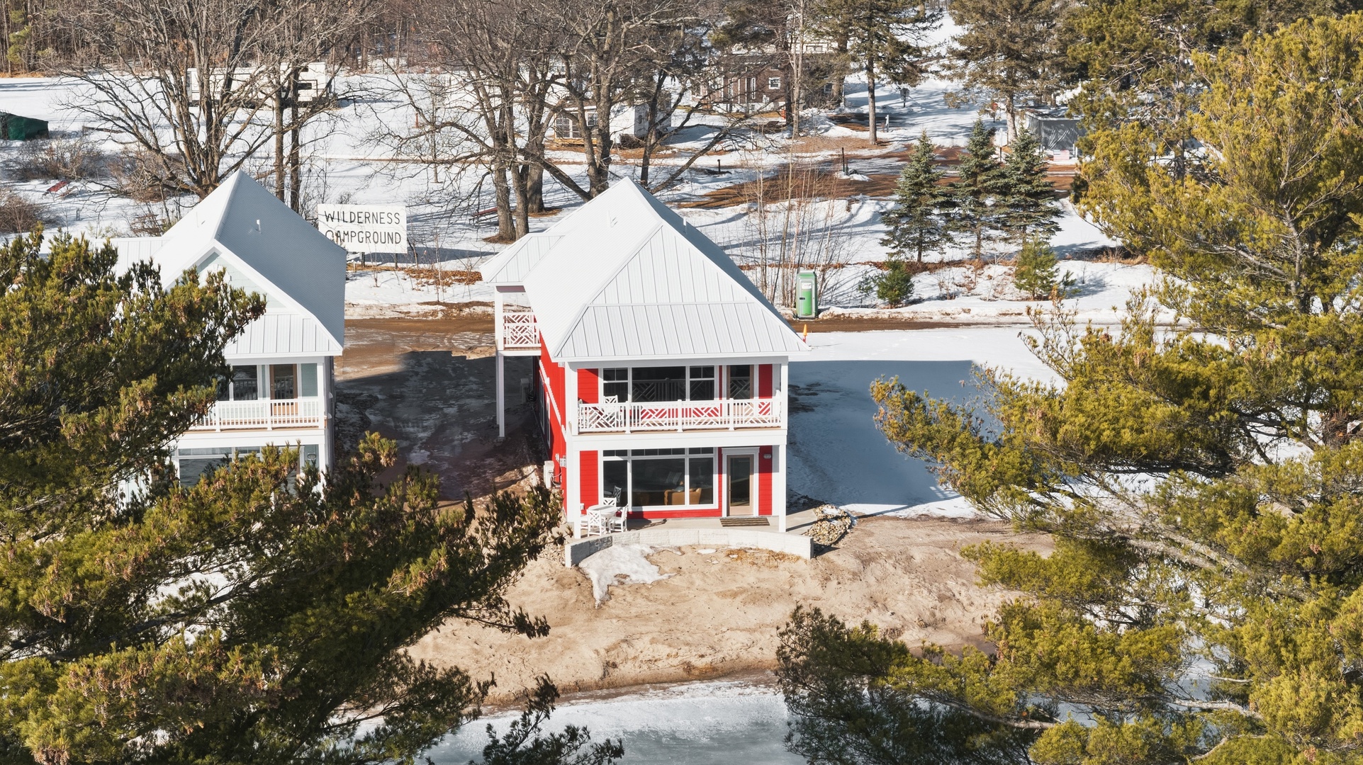 Aerial view of red house nestled among mature pine trees