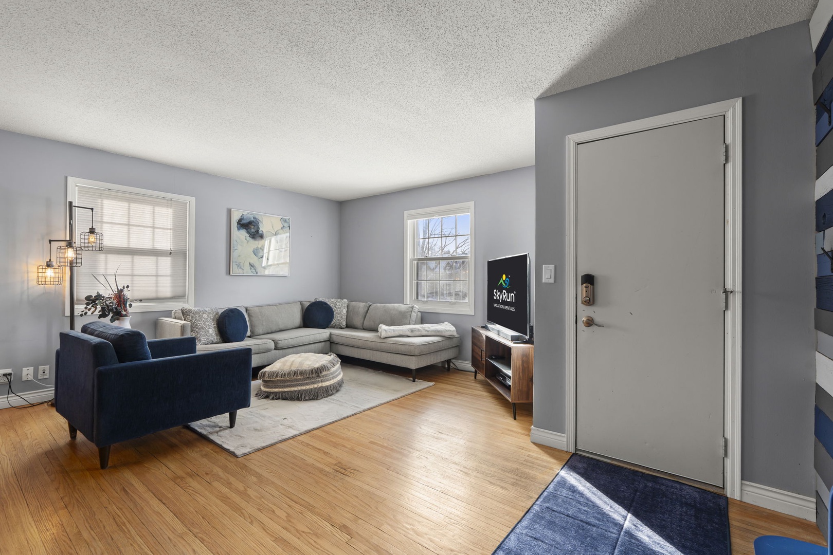 Relax in your spacious living room with plush sectional seating, modern entertainment center, and warm hardwood floors beneath your feet.