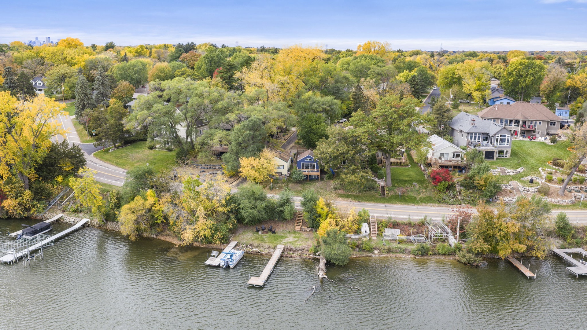 Aerial perspective of a charming lakeside neighborhood showcasing the property's waterfront access and peaceful, tree-lined surroundings.