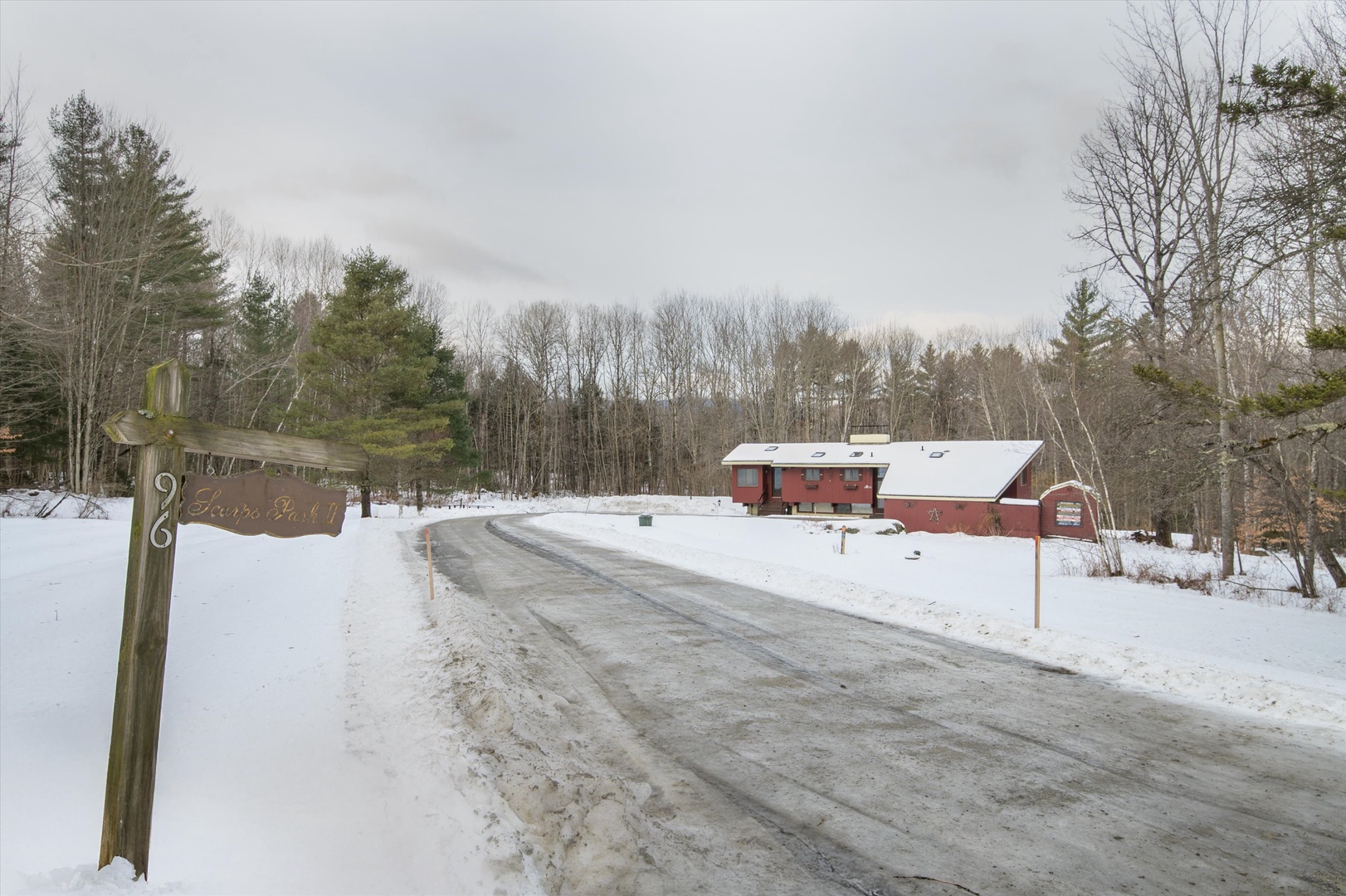 A peaceful winter arrival awaits at this charming property, nestled among snow-covered evergreens and bare winter trees.