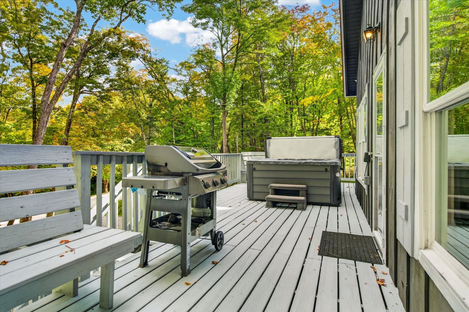 Your private deck surrounded by vibrant forest views, complete with hot tub and BBQ grill. Perfect for relaxing evenings under the trees.