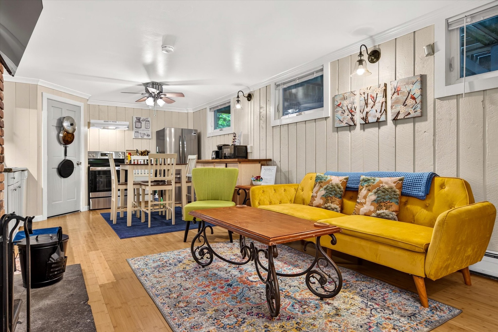Unwind in your bright and cheerful living space featuring a vibrant yellow sofa, charming vintage coffee table, and colorful décor that creates a welcoming home-away-from-home atmosphere.