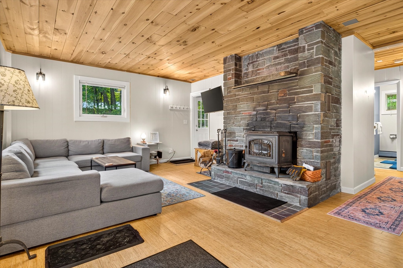 Unwind in your cozy living room, where a striking brick fireplace and warm wood-paneled ceiling create the perfect retreat after a day of adventure.