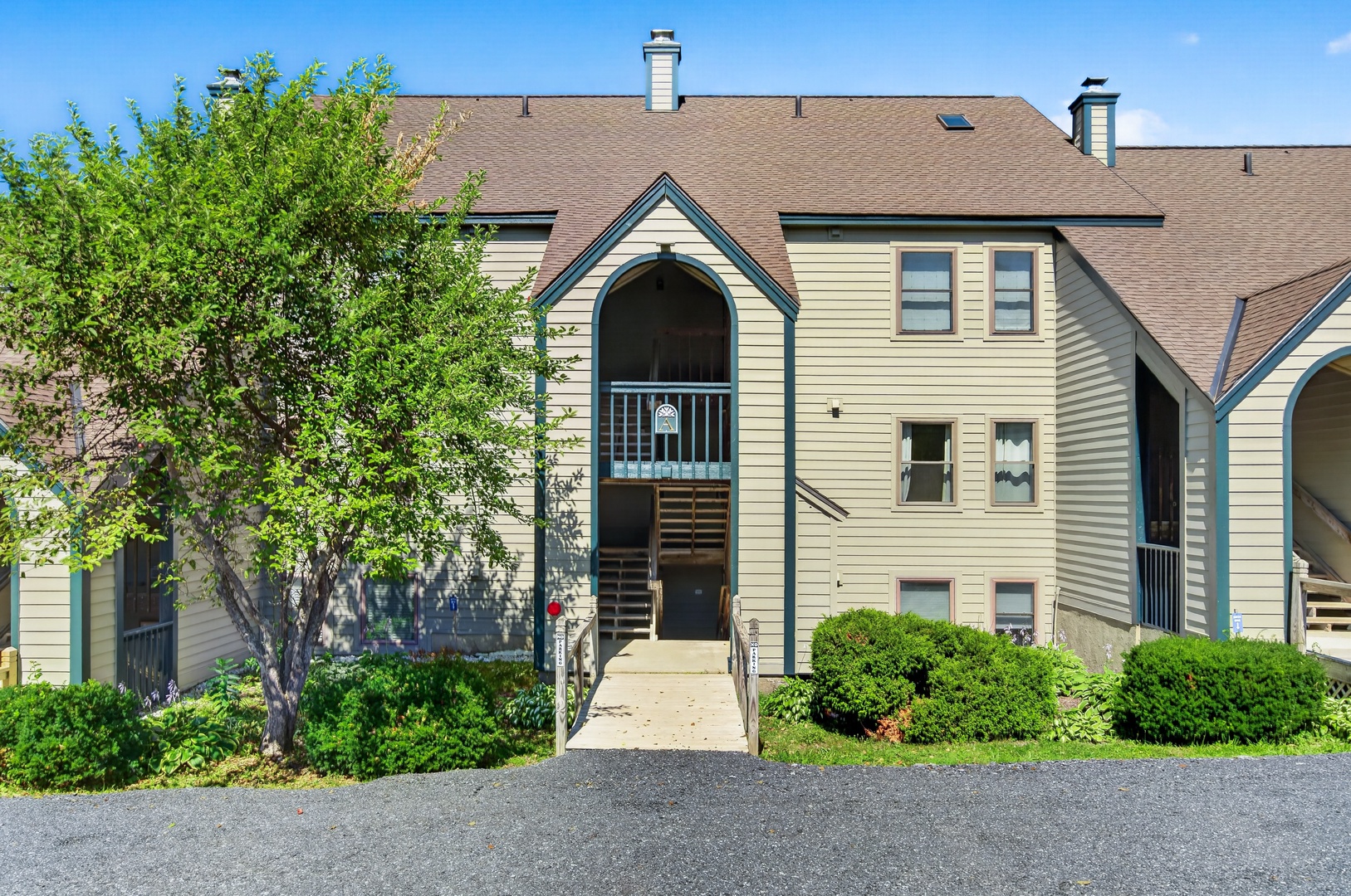 Multi-level property with distinctive arched entryway, mature landscaping, and welcoming front access. Paved parking and well-maintained exterior in a peaceful setting.