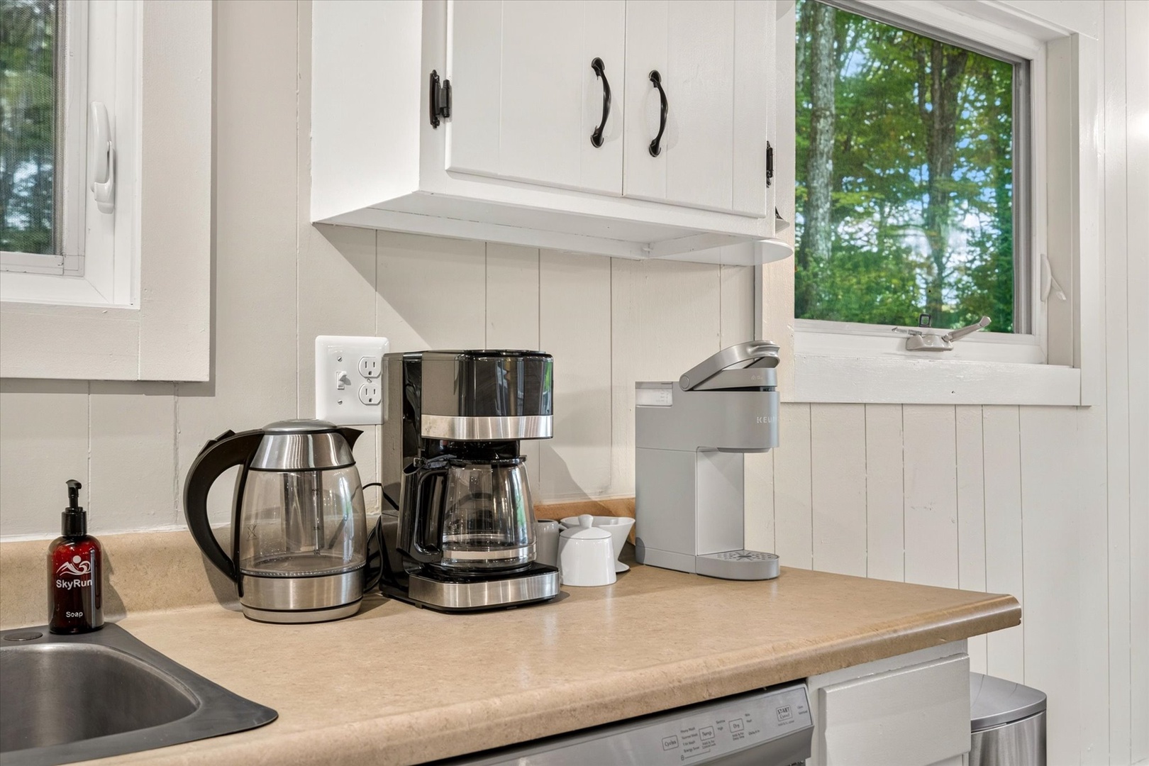 Your kitchen nook awaits with everything for a relaxing morning—brew fresh coffee, gaze at lush greenery through the window, and breathe in the serene forest setting.