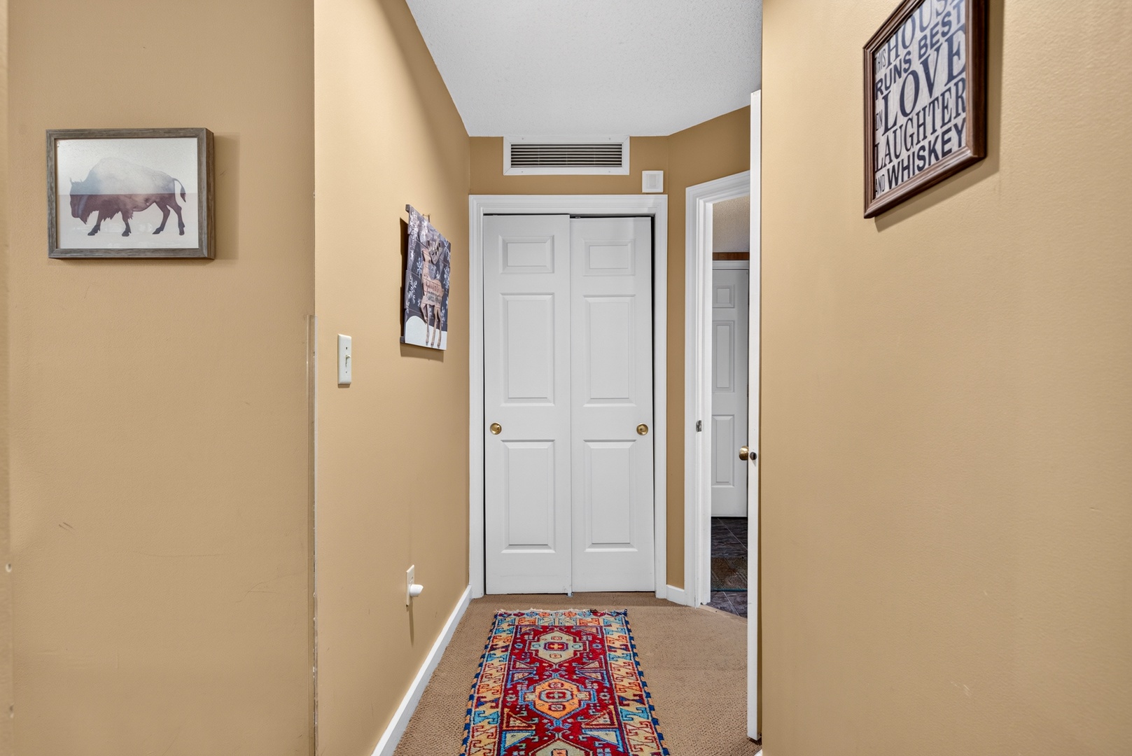 High ceilings and a welcoming hallway lead you to your private spaces, with thoughtful touches like artwork and a colorful rug adding warmth to your stay.