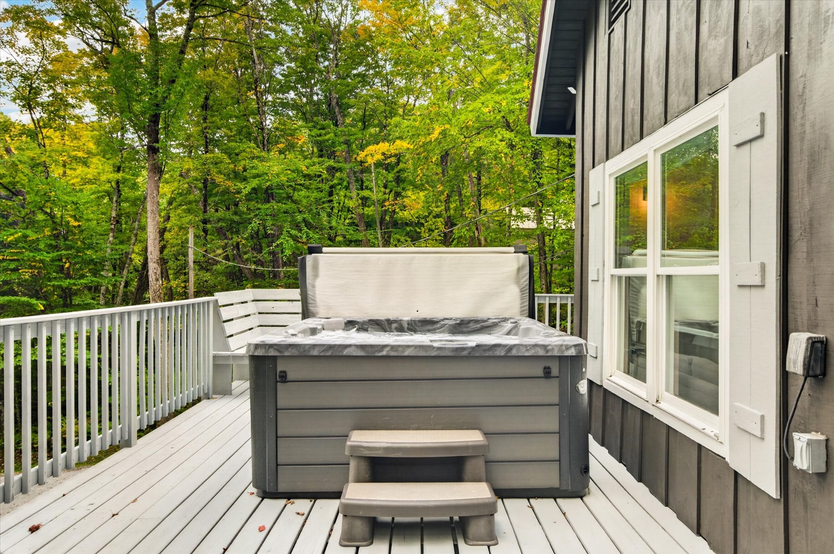 A private hot tub awaits on the spacious deck, surrounded by lush forest views that create your own peaceful woodland retreat.