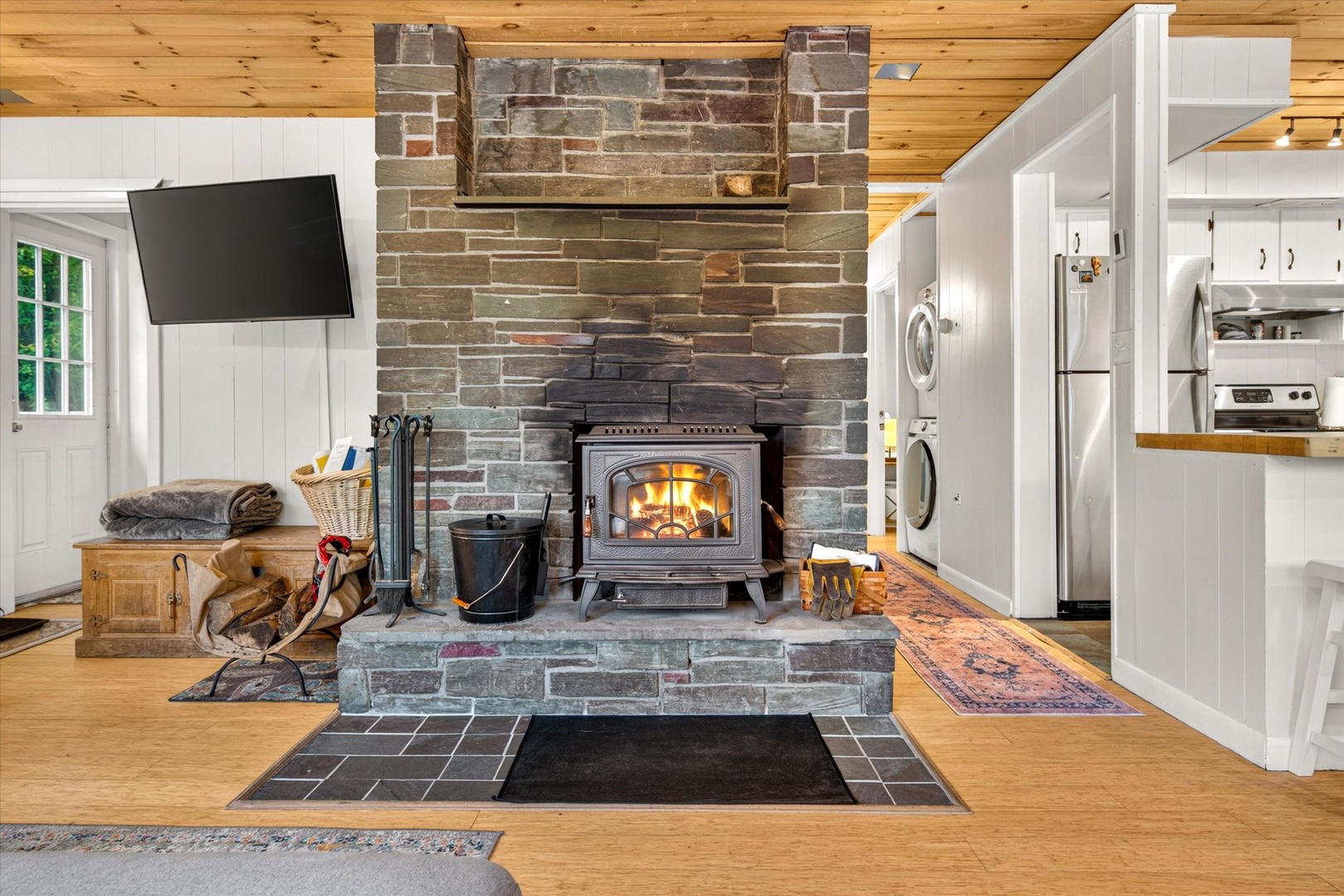 Gather around the rustic wood-burning stove, where warmth meets character beneath soaring timber ceilings, creating your perfect mountain retreat.
