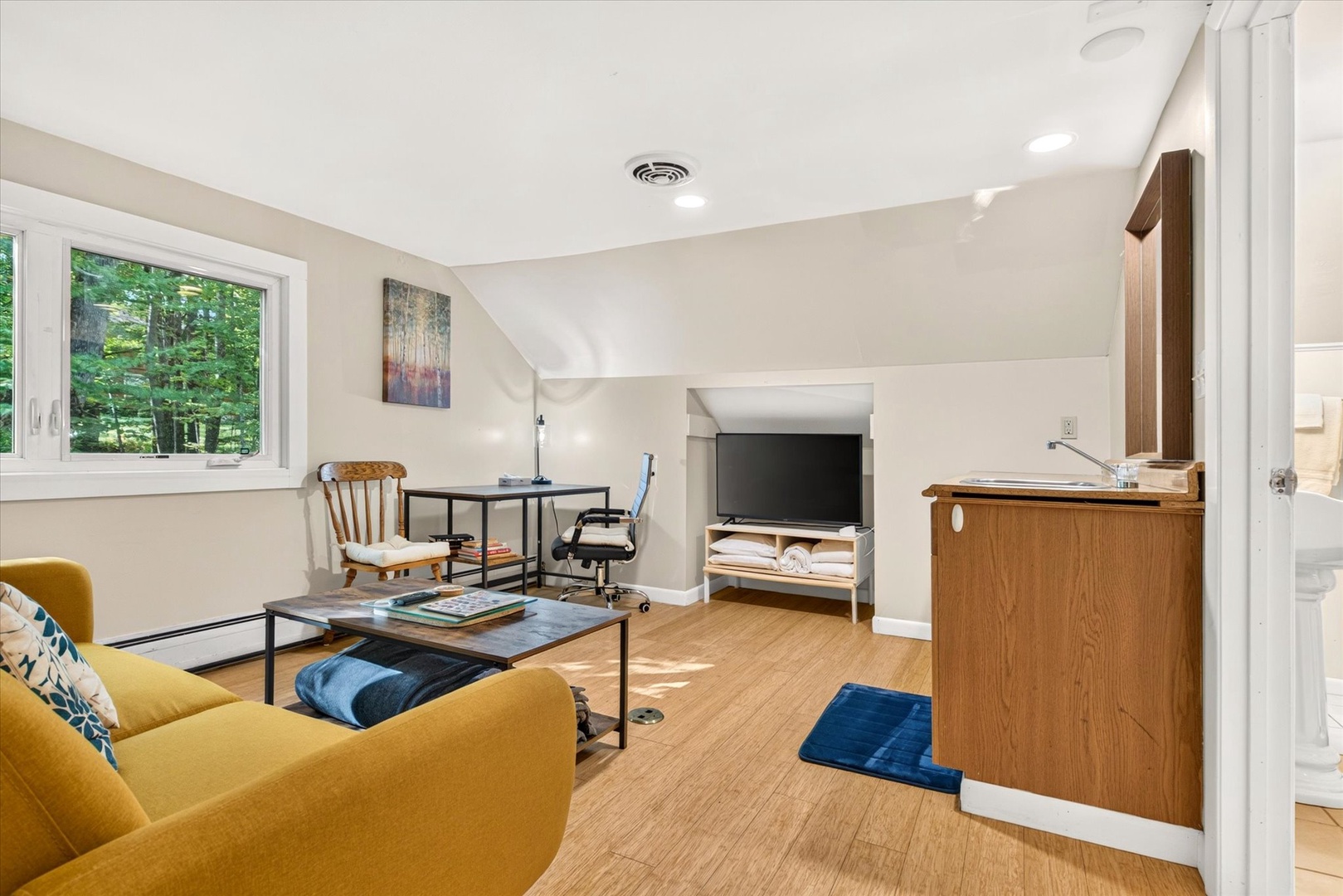 Settle into your serene workspace-meets-lounge, where natural light streams through forest views and inviting seating beckons you to unwind or stay productive in comfort.