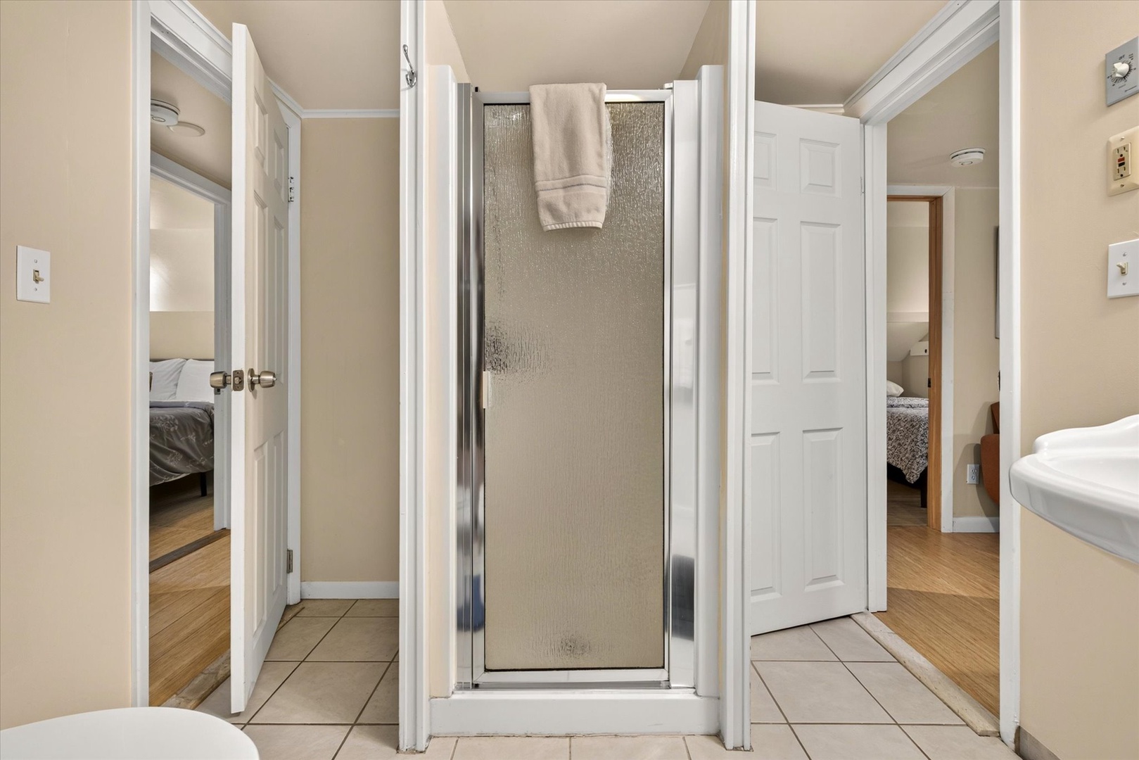 Your private bathroom features a sleek glass-enclosed shower, fresh towels, and warm neutral tones that create a serene space to refresh.