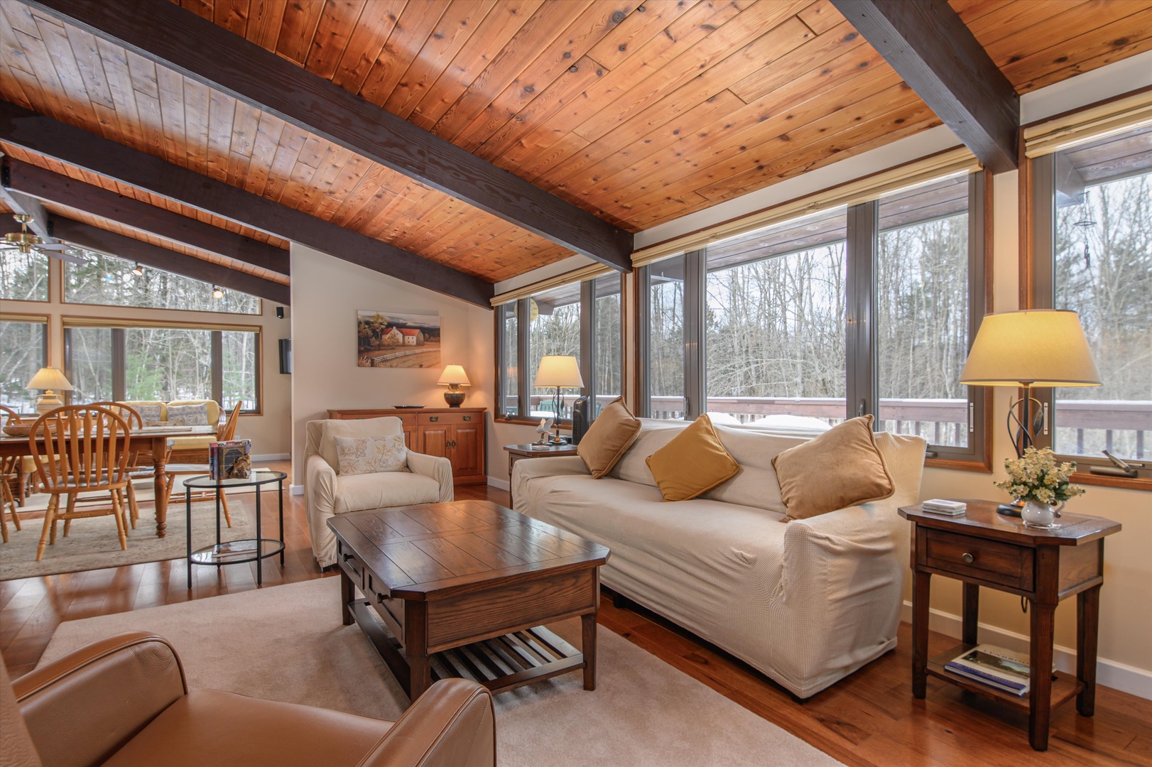 Sink into plush seating beneath stunning exposed beams while forest views frame your peaceful retreat through floor-to-ceiling windows.