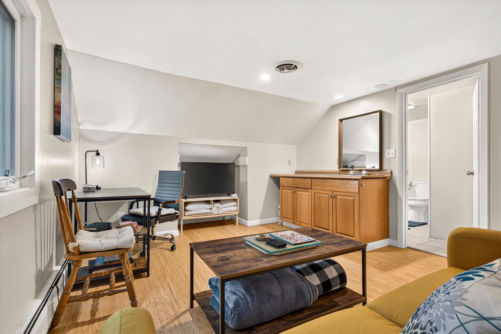 Bright and airy multipurpose space with warm wood tones, a cozy seating nook, and workspace—ideal for relaxing or catching up on plans during your stay.