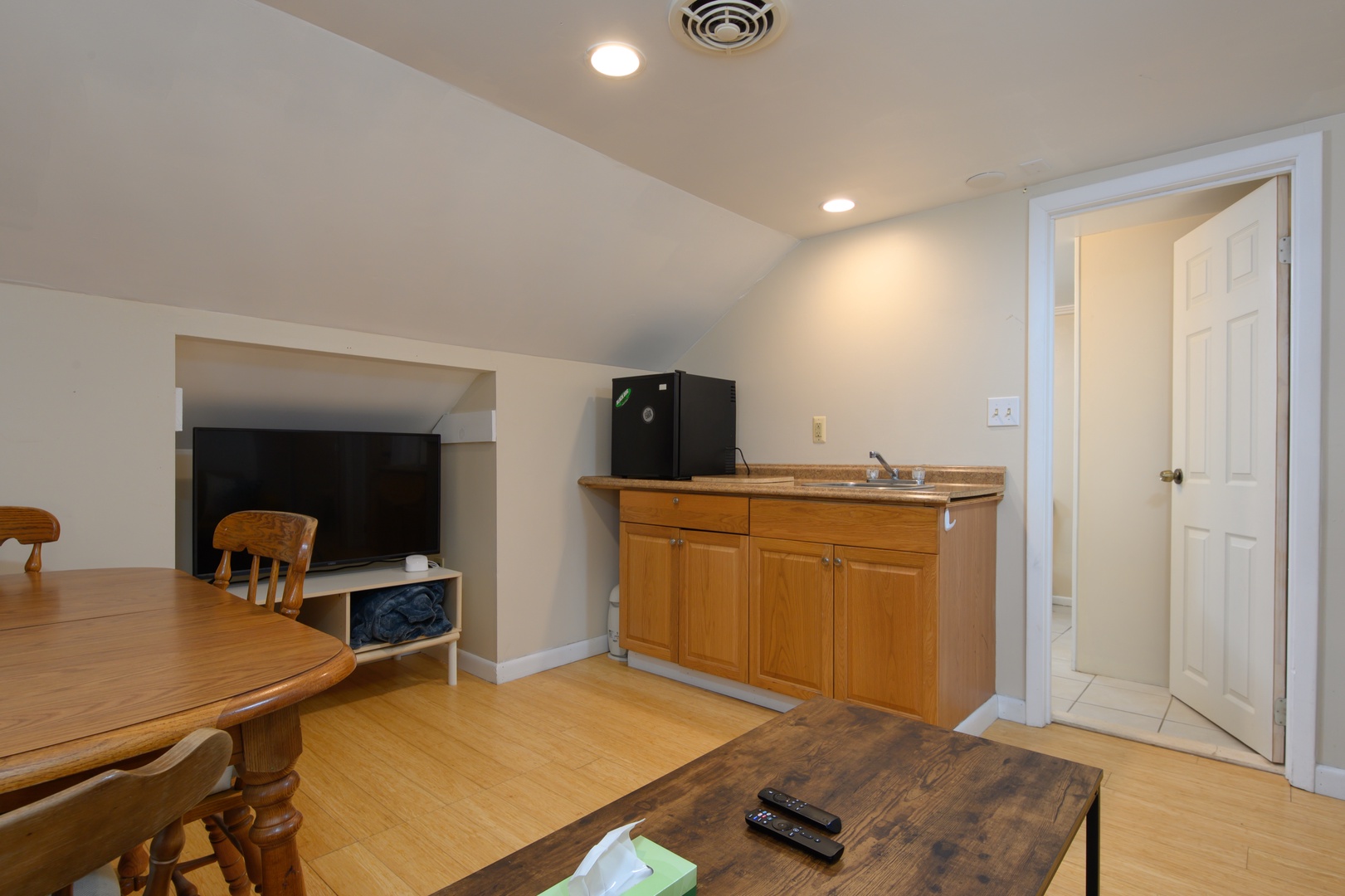 A relaxed upstairs hangout featuring a TV, dining table, and convenient sink—perfect for movie nights, games, or a casual snack break.