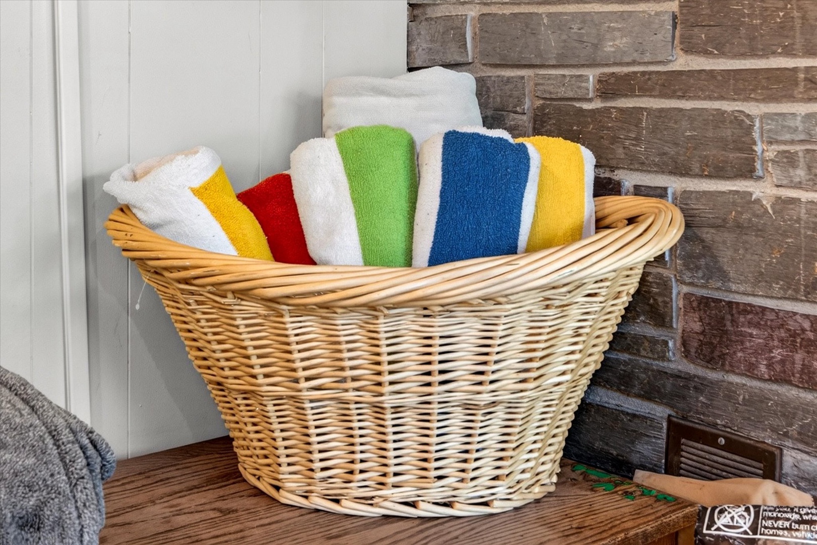 Bright, freshly laundered towels await in a cozy woven basket—your colorful welcome after a refreshing shower or swim.