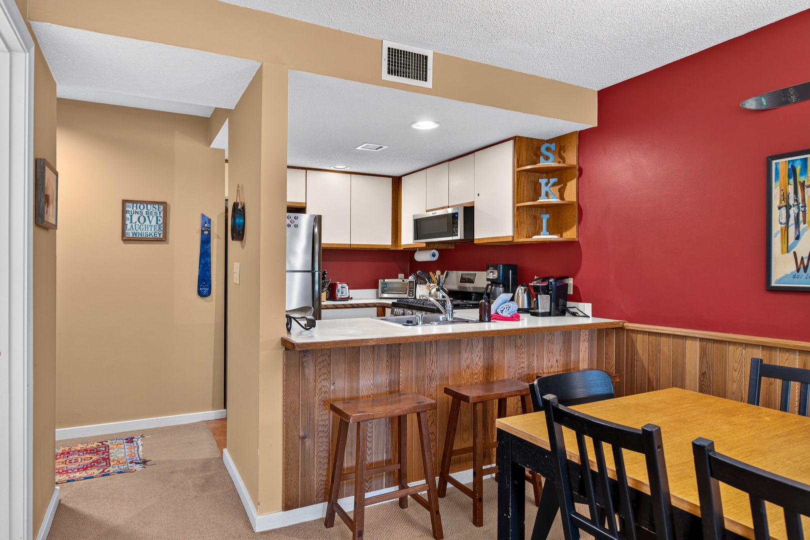Your fully equipped kitchen features modern appliances, a breakfast bar with seating, and vibrant décor—perfect for preparing meals and enjoying casual conversations over coffee.