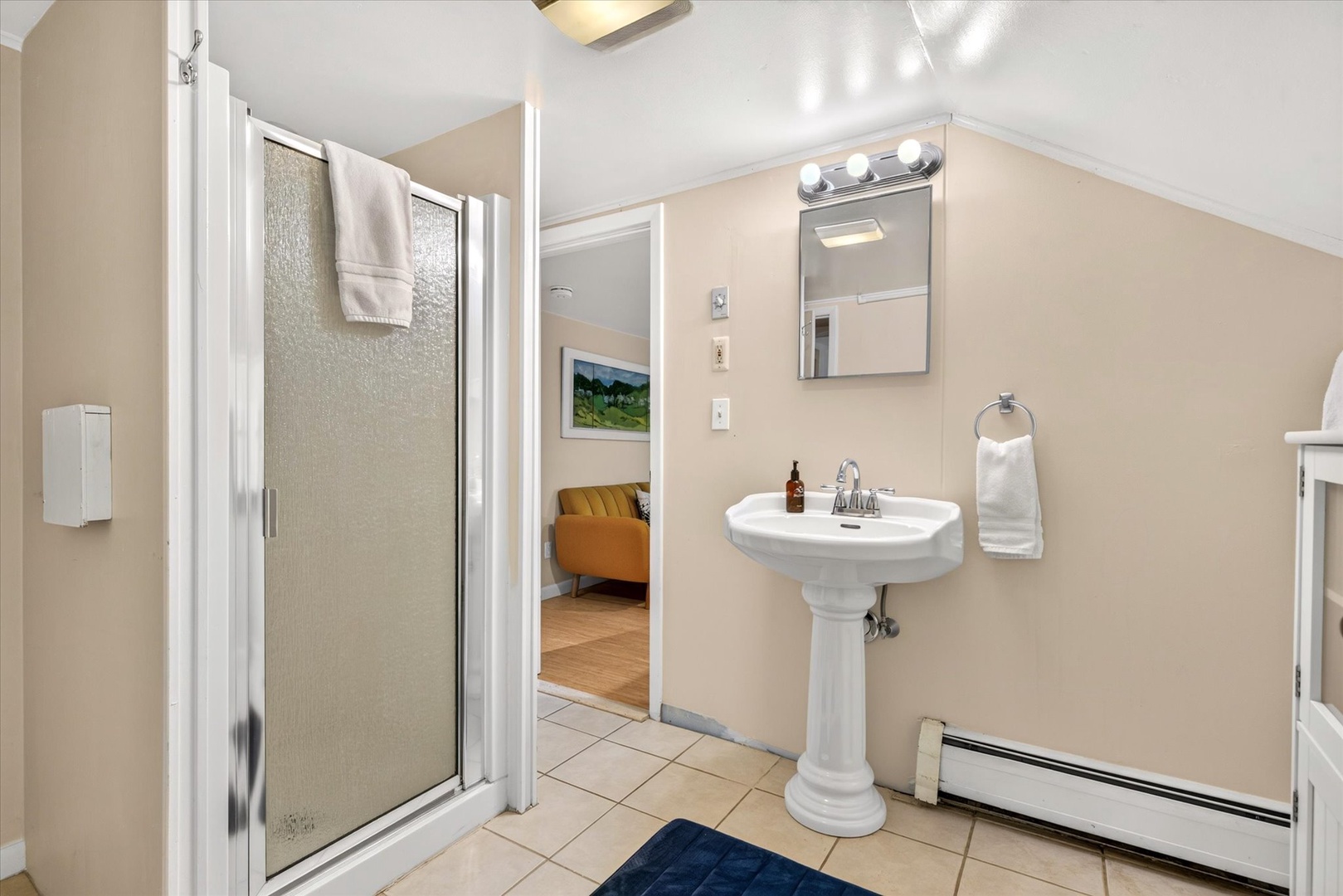 Step into your serene private bathroom with classic pedestal sink, walk-in shower, and fresh towels waiting for you—a clean, comfortable space to refresh and unwind.