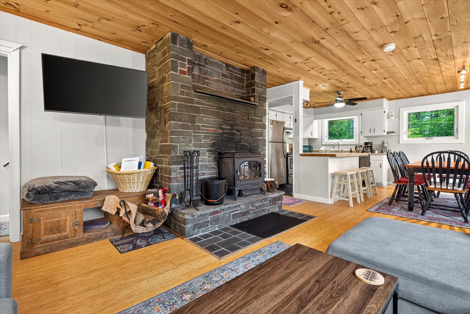 Your cozy retreat awaits with rustic wood ceilings and a charming brick fireplace creating the perfect ambiance for relaxation. The open-concept space flows seamlessly from living area to kitchen, all with peaceful forest views.