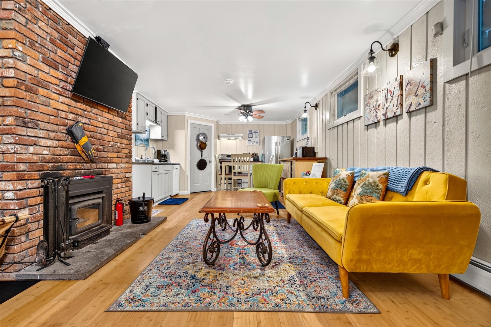 Sink into the plush golden sofa in this warm, character-filled living space. A cozy wood-burning fireplace and exposed brick create the perfect atmosphere for relaxation and gathering.