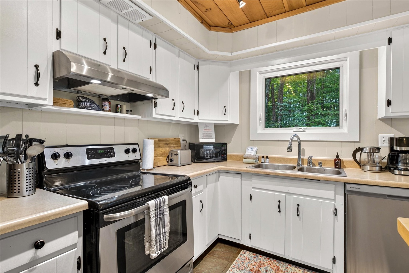 Your fully-equipped kitchen invites easy meal prep, with crisp white cabinets, warm wood countertops, and a natural green view from the window that brings the outdoors in.