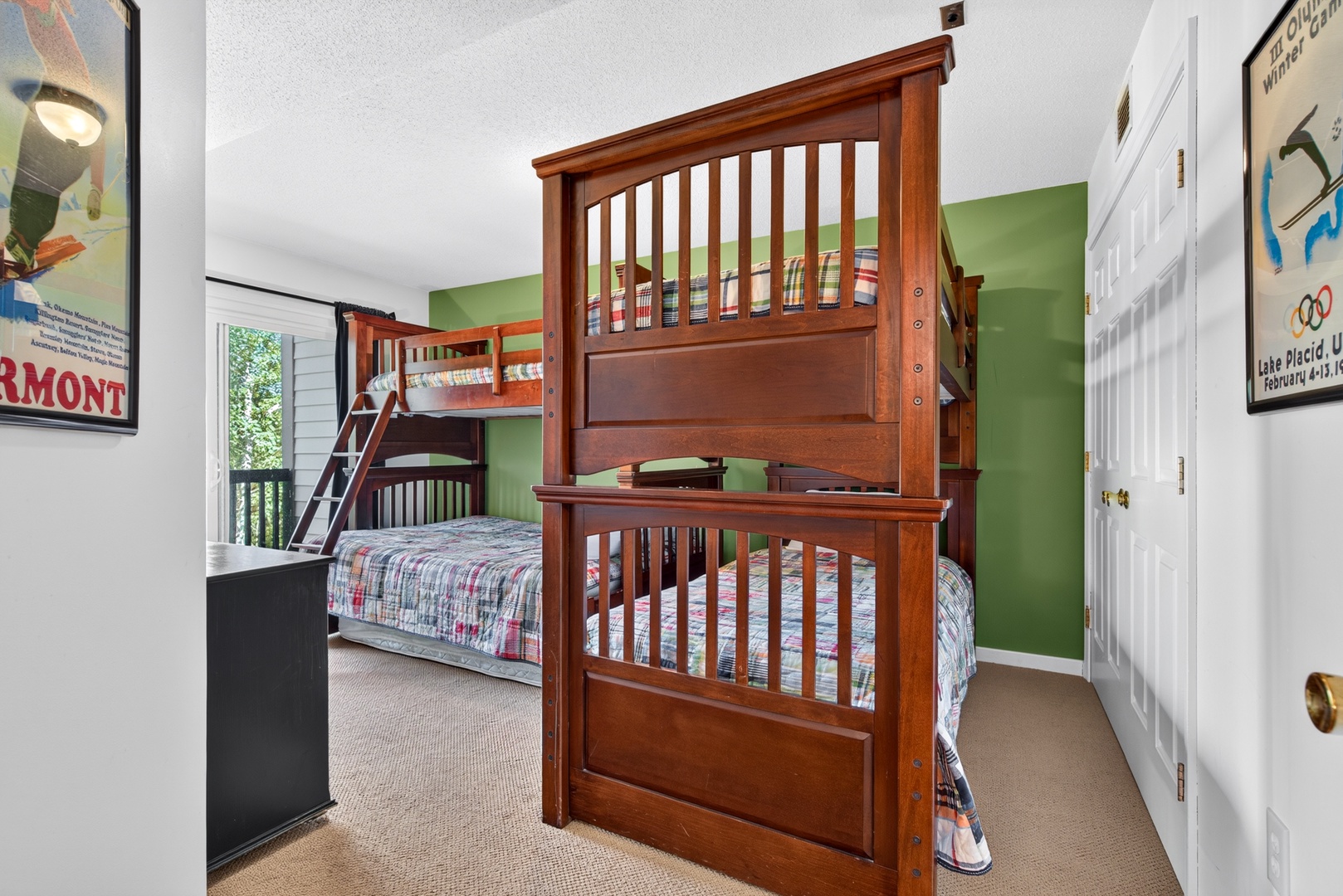 Your group will love this cozy room with sturdy bunk beds perfect for kids or friends. The bright green accent wall and vintage travel posters add cheerful character, while natural light from the window keeps the space feeling fresh and inviting.