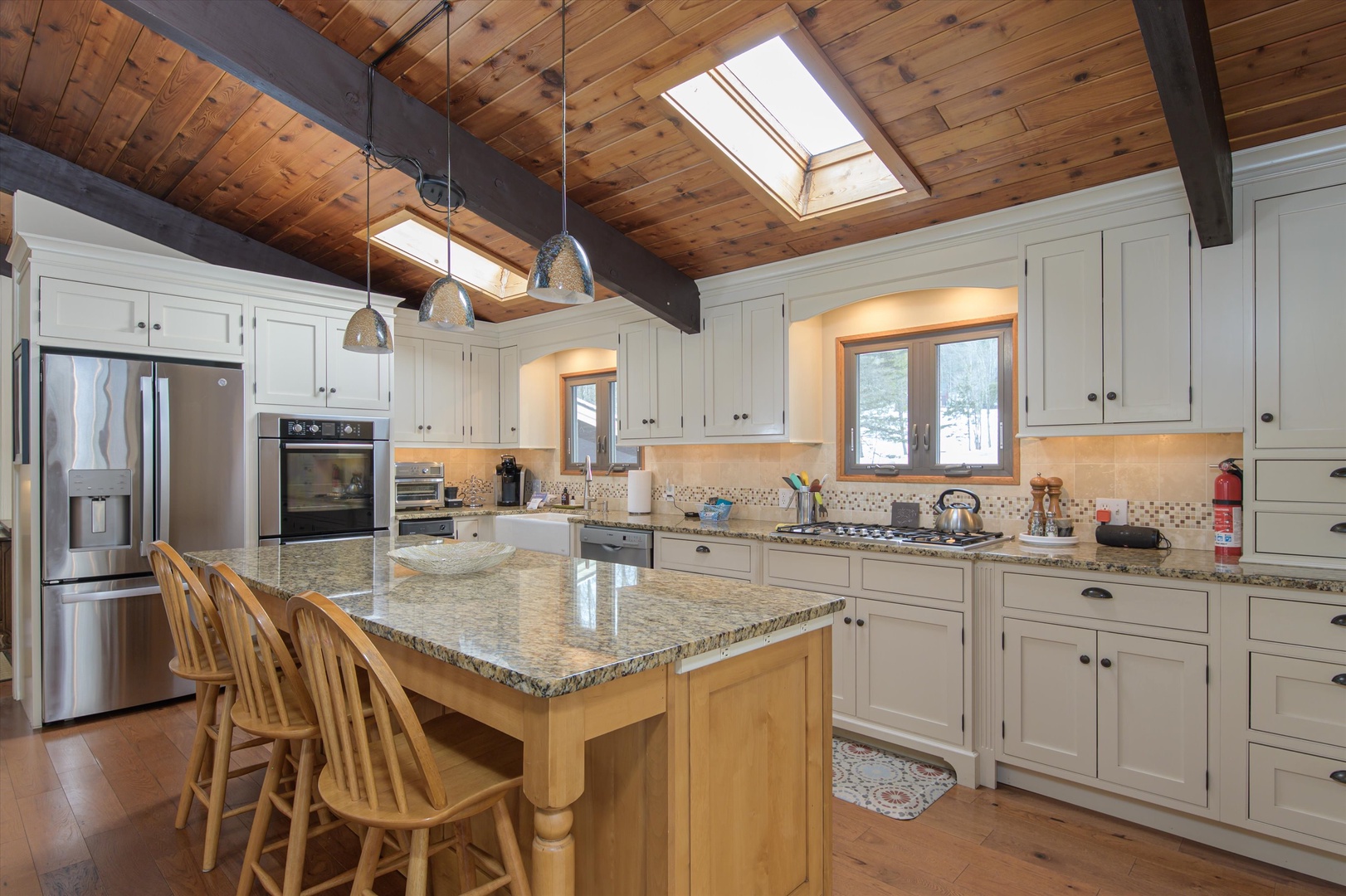 Prepare family meals in this beautiful kitchen featuring granite countertops, stainless steel appliances, and rustic wood beams overhead.