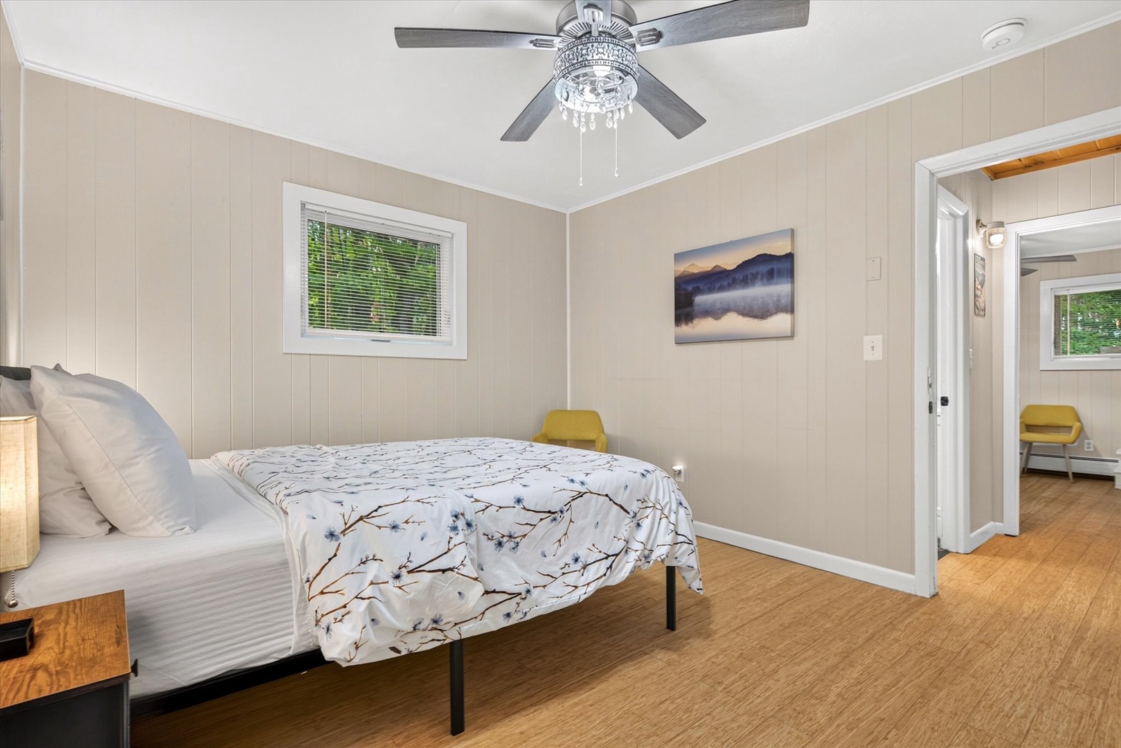 Drift off under the gentle breeze of the ceiling fan in this serene bedroom. Soft tones, natural light, and warm wood floors create your perfect retreat.