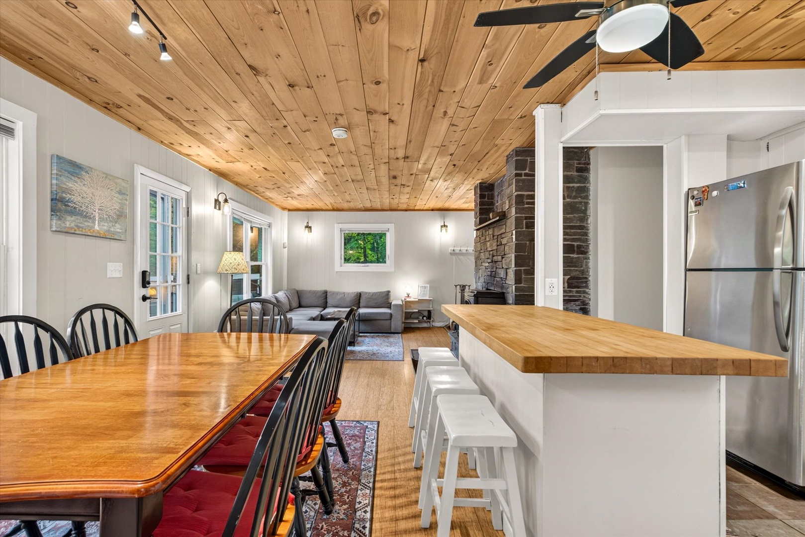 Beautiful open-concept living with warm wood ceilings and natural light. The kitchen island and dining area flow seamlessly into the living space, perfect for gathering and relaxing.