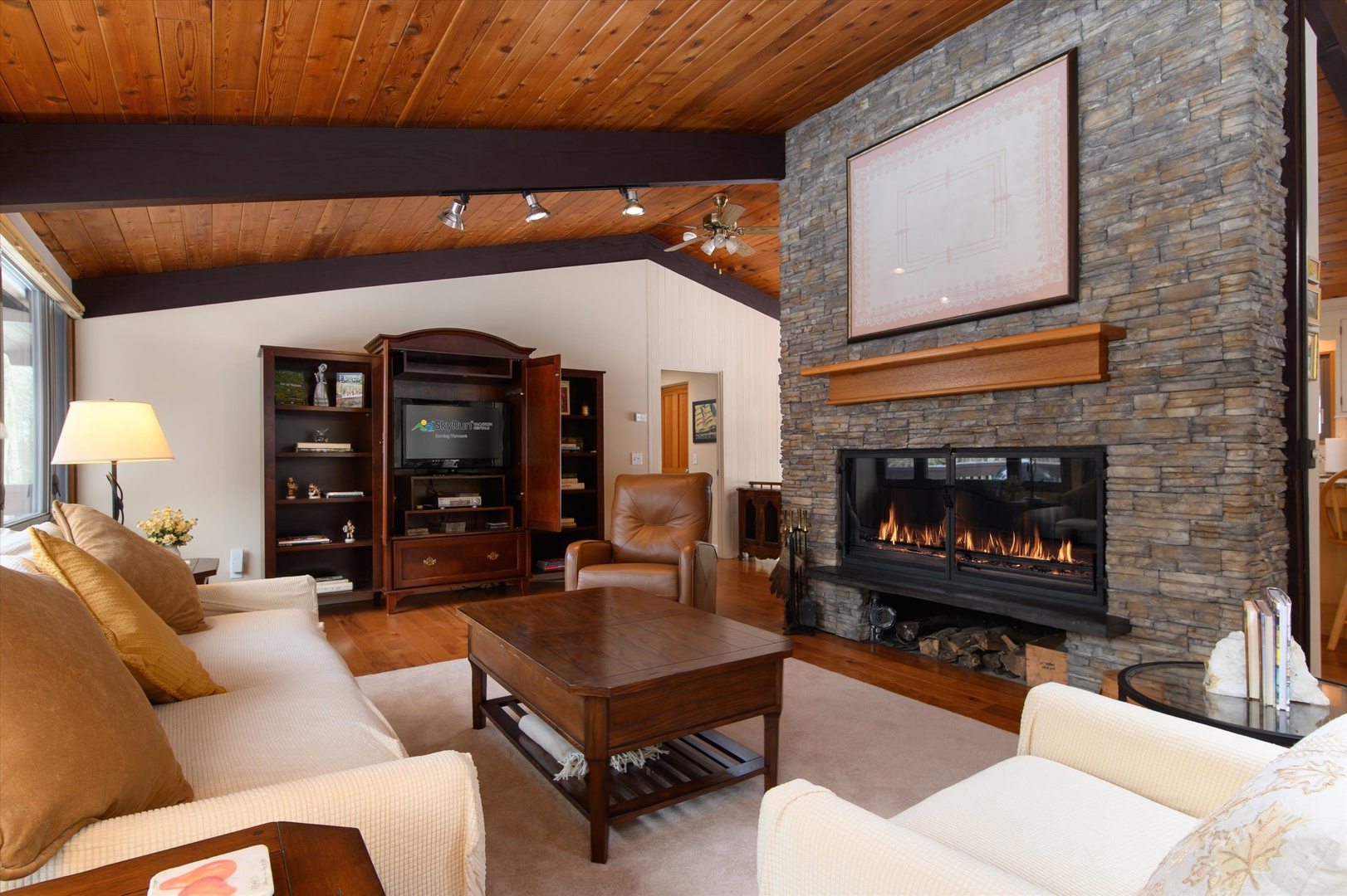 Curl up in your cozy living room featuring a stunning stone fireplace, rich wood beams, and plush seating for perfect mountain evenings.