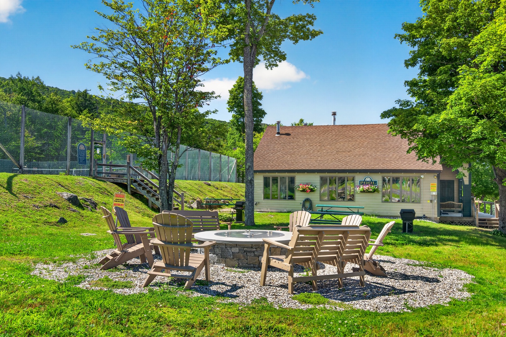 Nestled in lush greenery, this property offers a peaceful mountain retreat with a fire pit gathering area, outdoor games, and hillside recreation space.