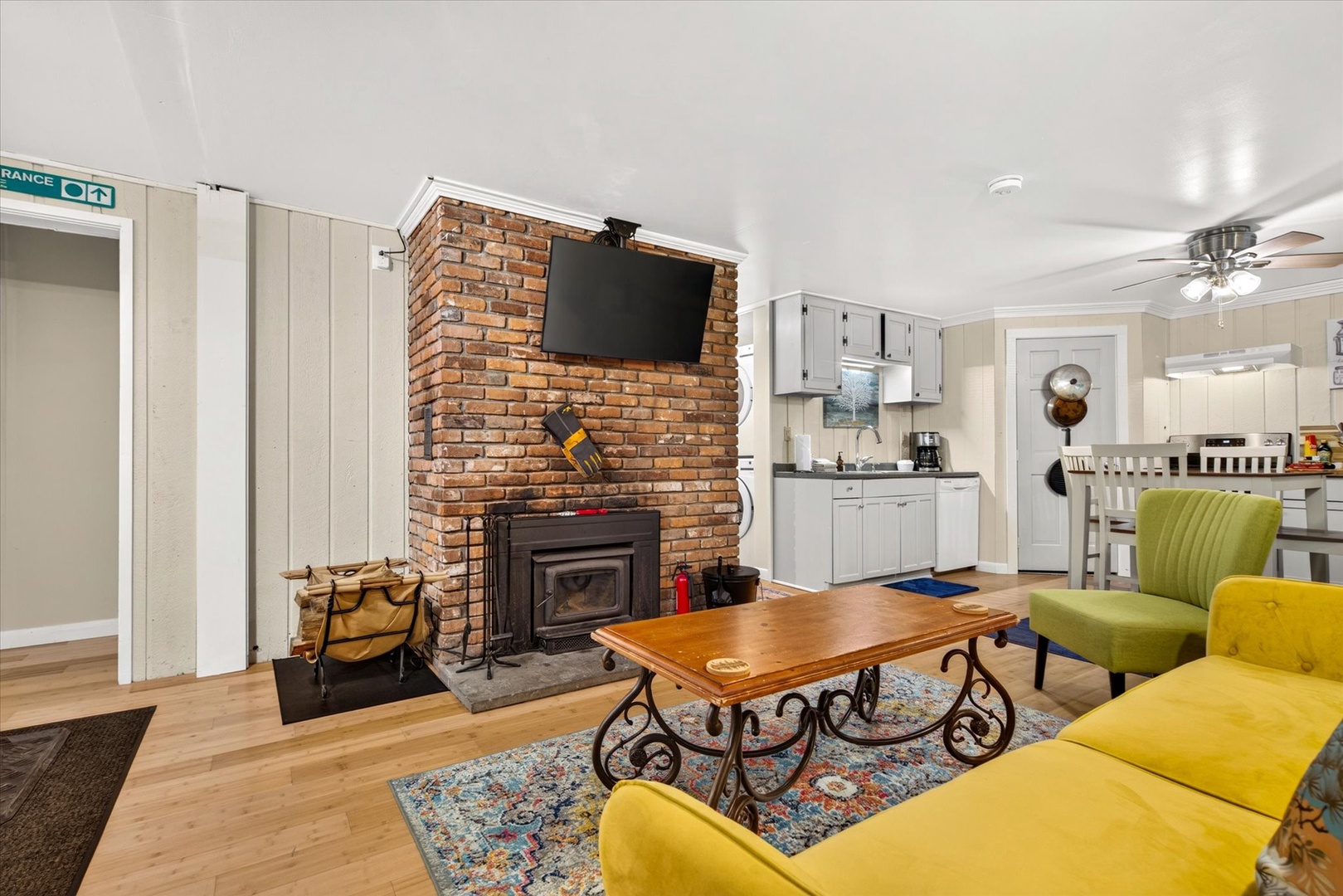 Unwind in your charming living space where a warm brick fireplace meets modern comfort. Bright pops of yellow seating invite you to relax while the open kitchen stands ready for your home-cooked meals.