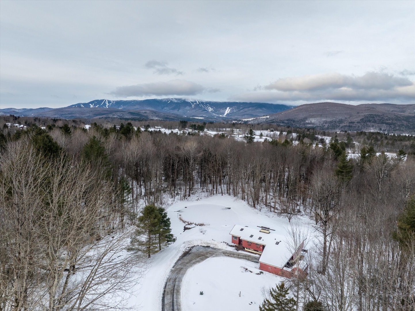 Bird’s-eye view of the property nestled among snow-dusted trees in a quiet mountain landscape.