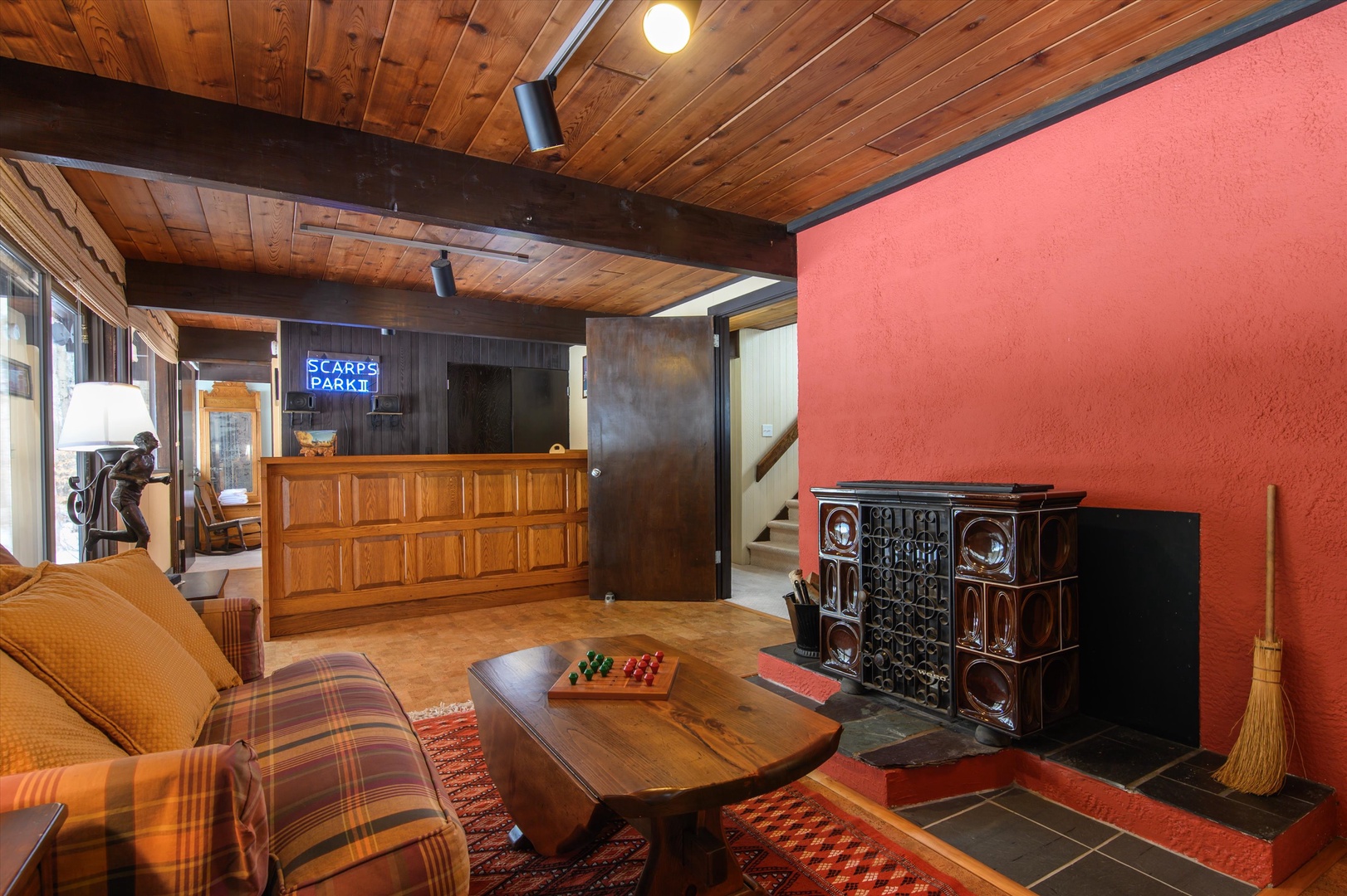 Gather in this retro-style basement with a bar, tv, cozy seating, and a decorative fireplace, full of character and charm.