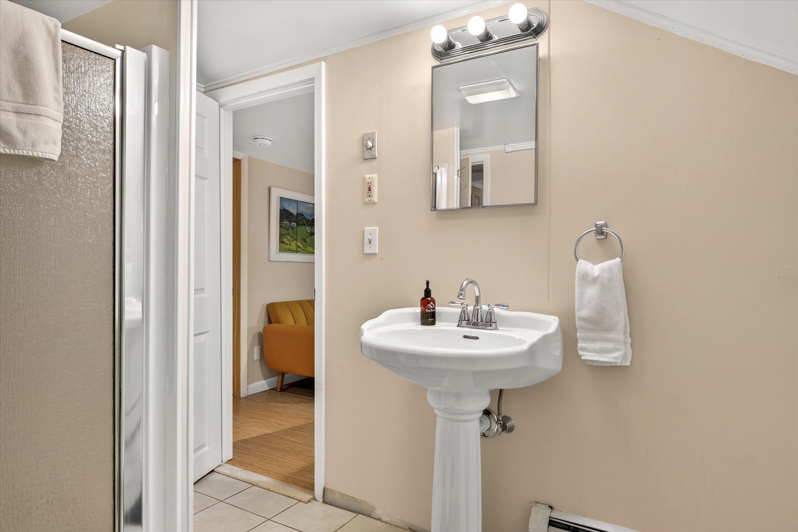 Your bathroom features a classic pedestal sink with soft lighting and fresh towels, creating a clean and welcoming retreat after a day of exploring.