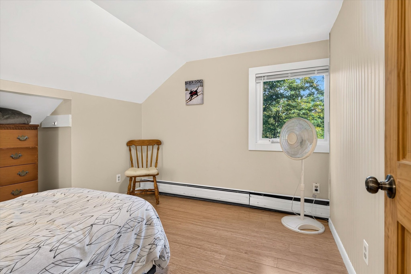 Your bright bedroom offers a peaceful spot to unwind, with natural light streaming through the window and vaulted ceilings creating an airy, open feel.