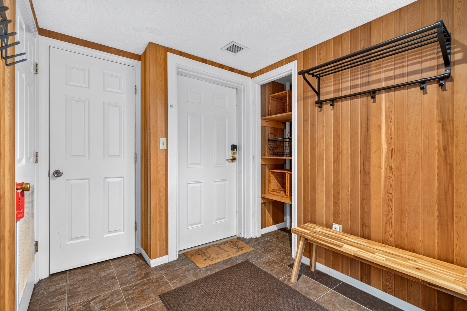 Step into your cozy cabin-style entryway with warm wood paneling, open storage for all your gear, and plenty of hooks and shelving to keep everything organized and ready for your next adventure.