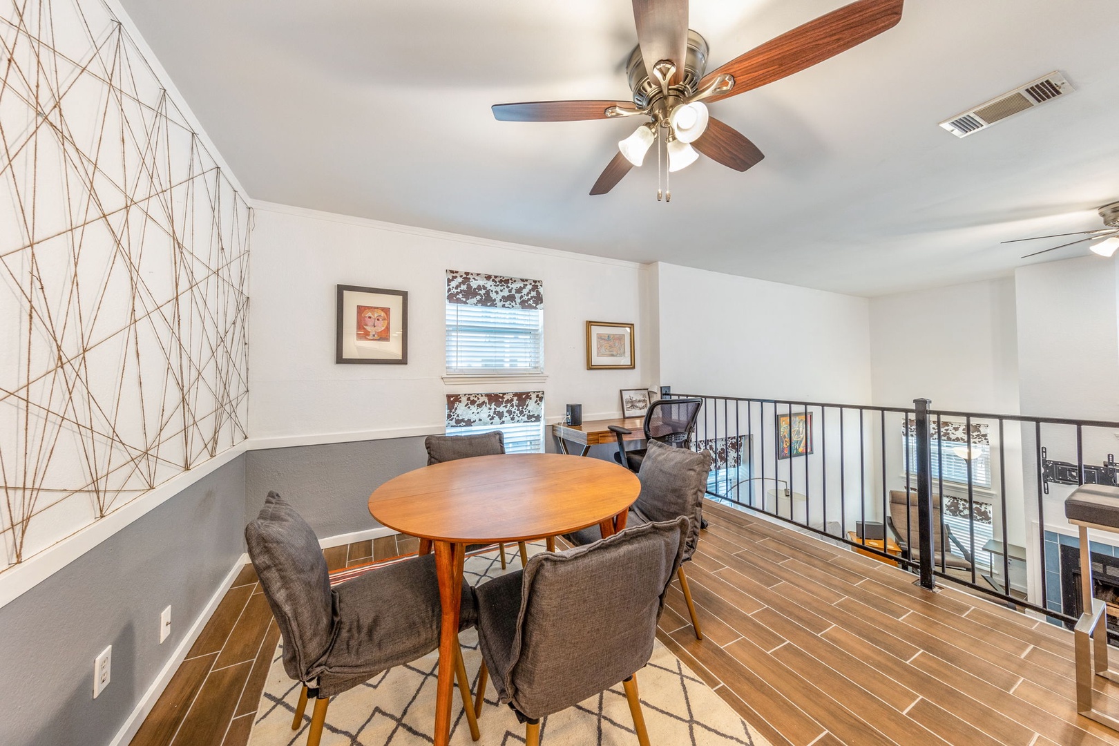 Settle into your cozy loft workspace with a warm ceiling fan above and a charming round table perfect for catching up on emails or enjoying morning coffee.