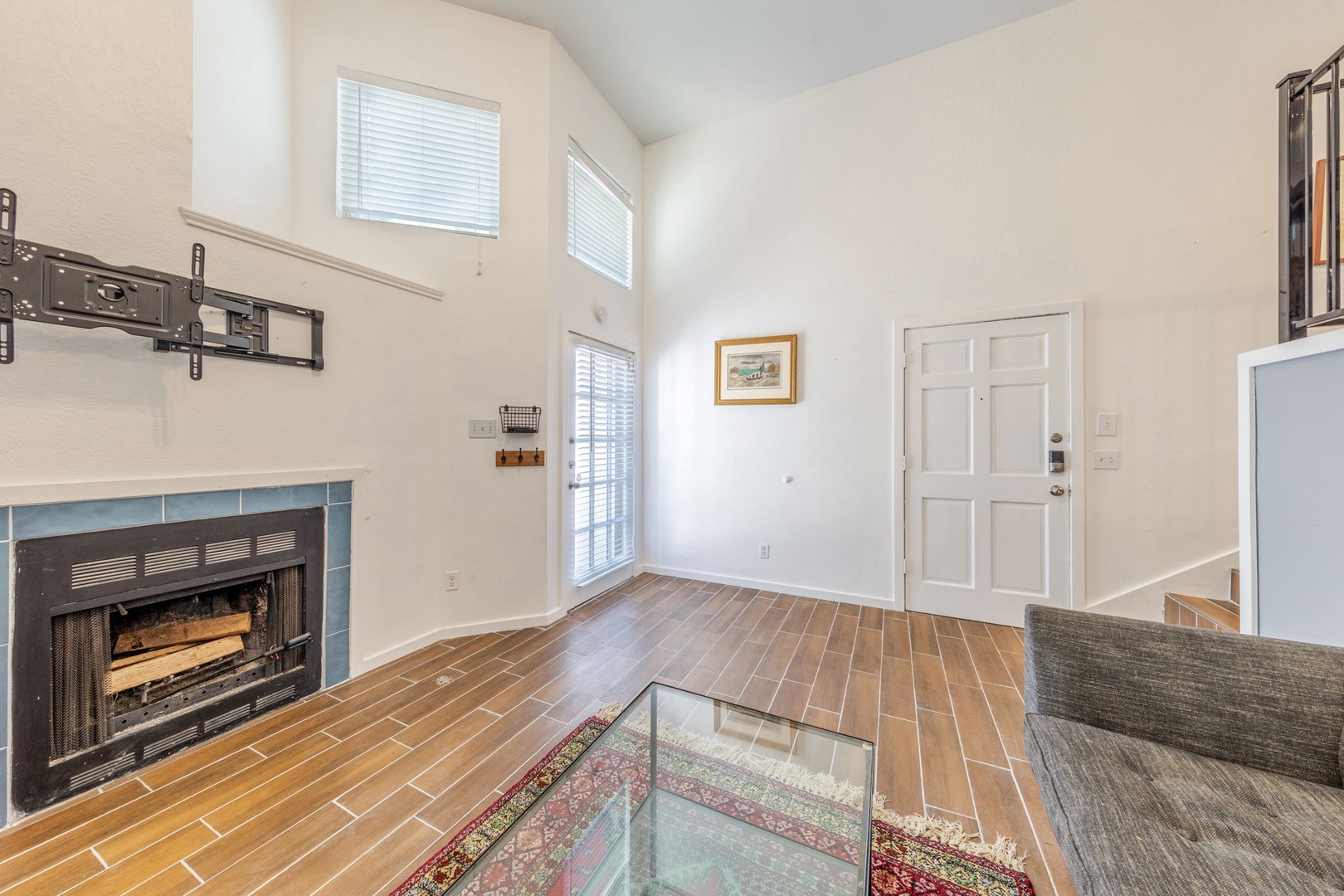 TV currently installed above fireplace not shown.  Step into your bright, airy living space with soaring ceilings and wood-style floors that invite you to unwind by the cozy fireplace after a day exploring.