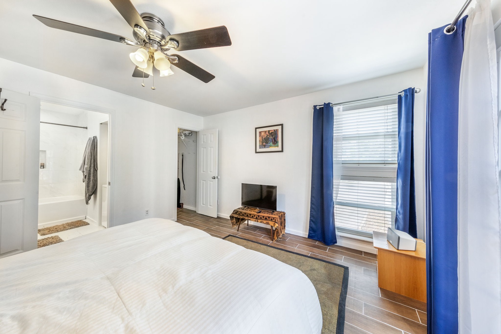 Unwind in your bright bedroom with plush bedding, ceiling fan, and flat-screen TV. The adjoining bathroom and ample natural light create your perfect restful retreat.
