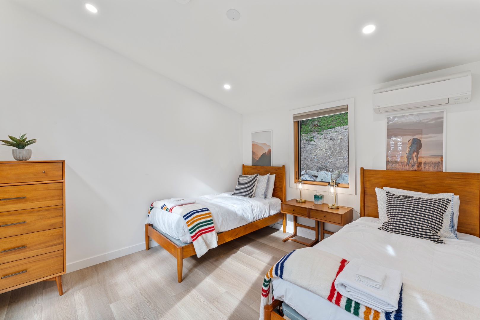 Your twin bedroom features mid-century charm with warm wood furnishings, crisp linens, and a peaceful garden view.