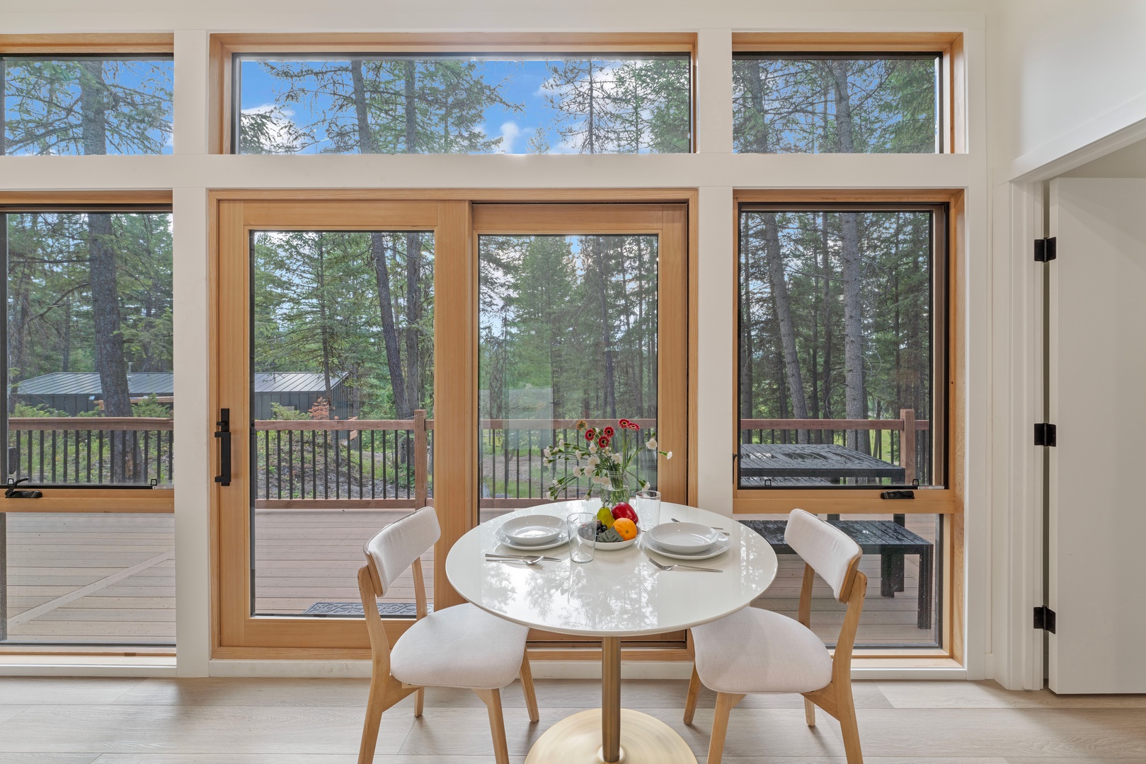 Enjoy meals surrounded by floor-to-ceiling windows showcasing peaceful forest views from your bright dining space.