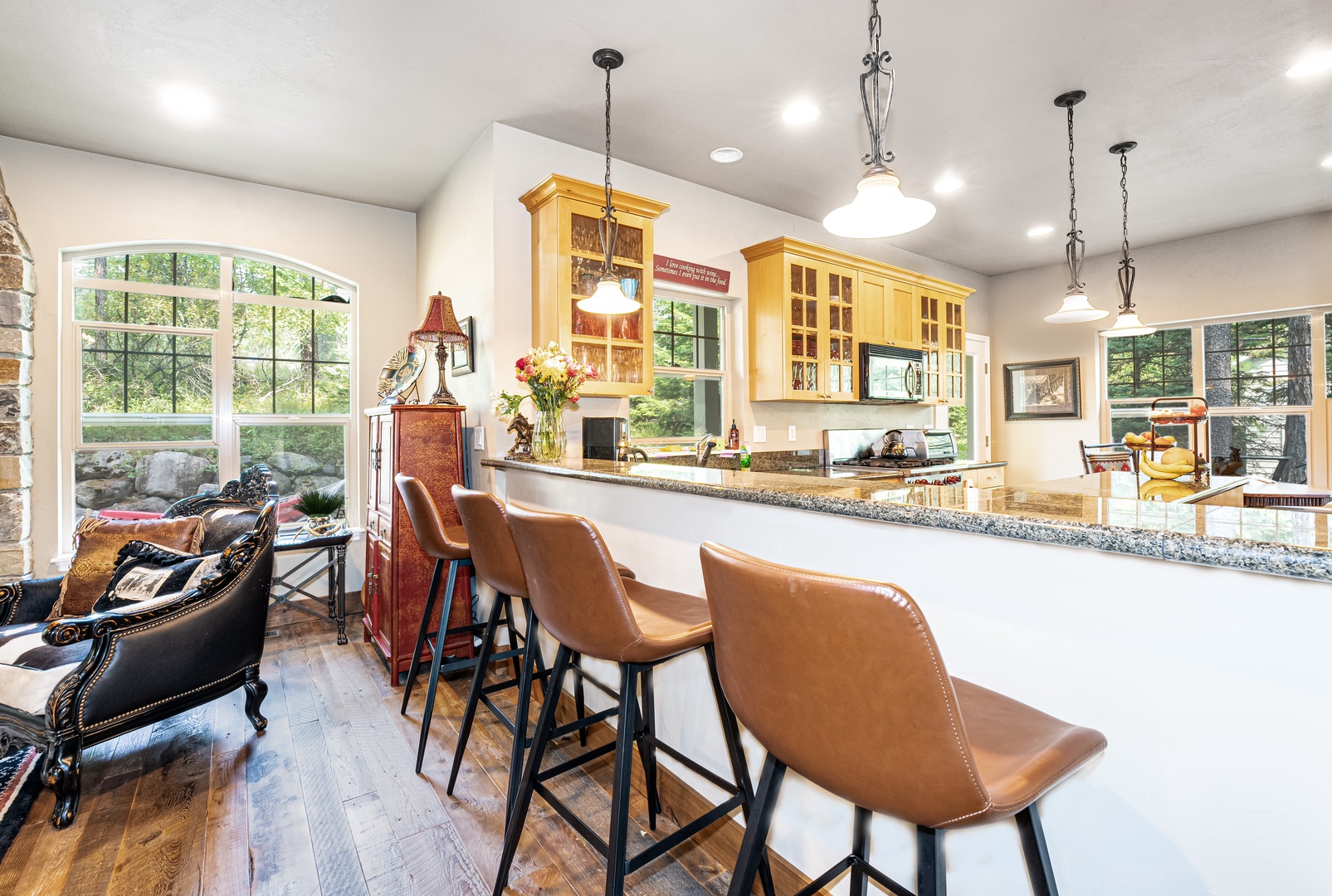 Enjoy morning coffee at the spacious kitchen island with sunshine streaming through arched windows overlooking lush greenery. The fully equipped kitchen opens to inviting living areas perfect for relaxing or gathering.
