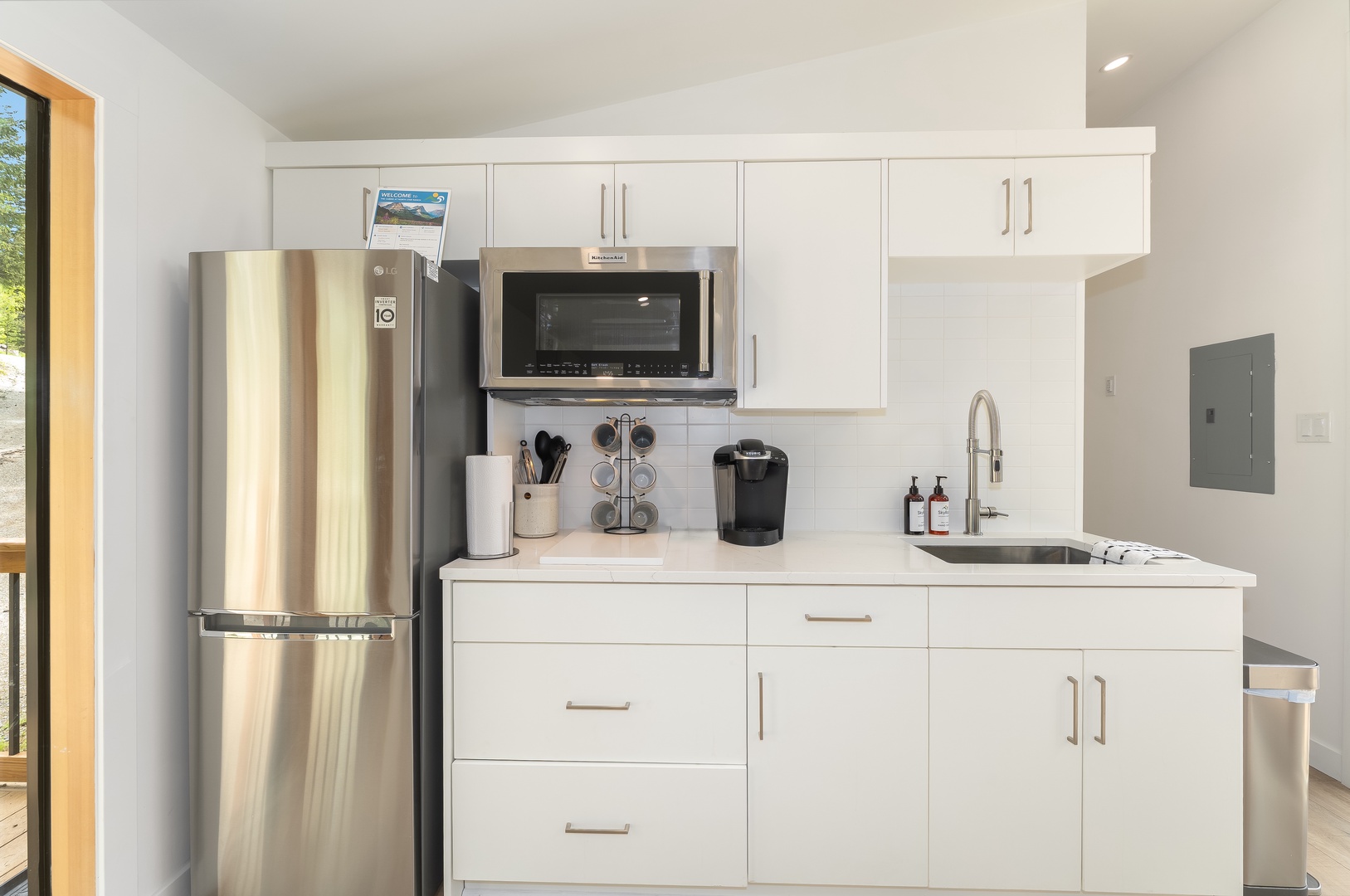 Your sleek kitchenette awaits with stainless steel appliances, modern white cabinetry, and everything you need to brew morning coffee or prep a quick meal in comfort.