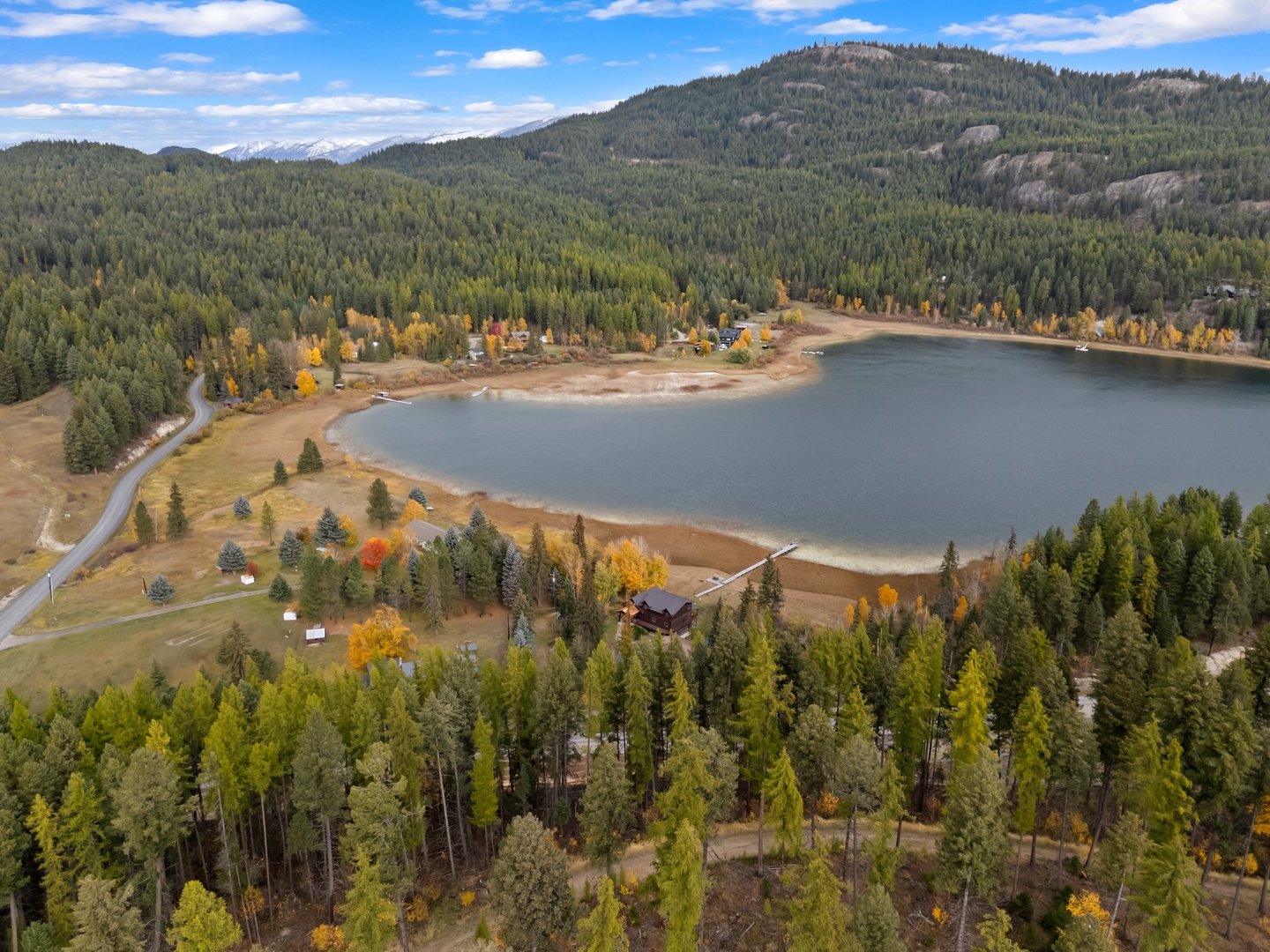 Stunning aerial perspective reveals a pristine mountain lake surrounded by vibrant autumn foliage and forested peaks.