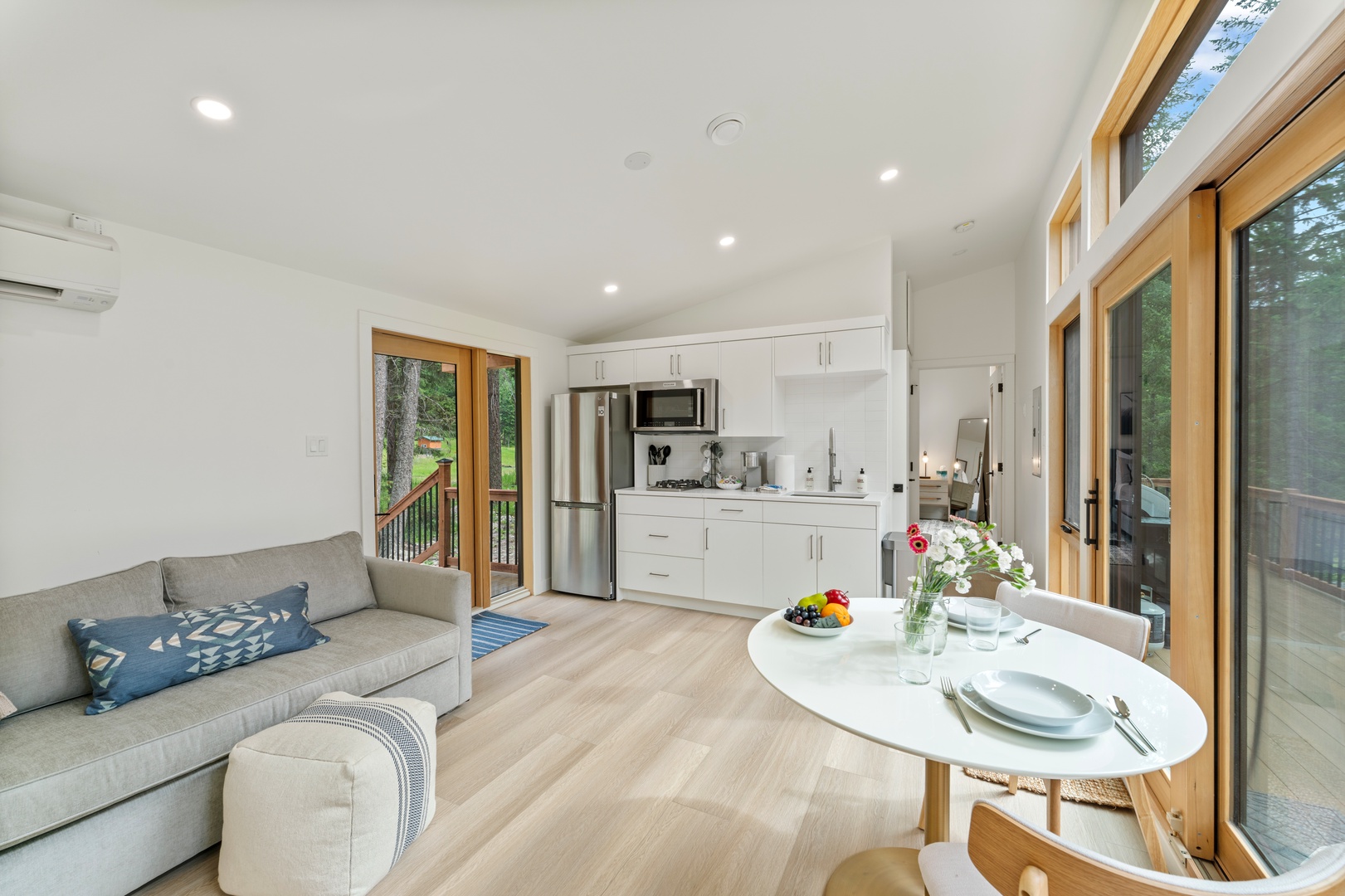 Relax in your bright open-plan space where modern comfort meets natural beauty through expansive windows overlooking lush greenery.