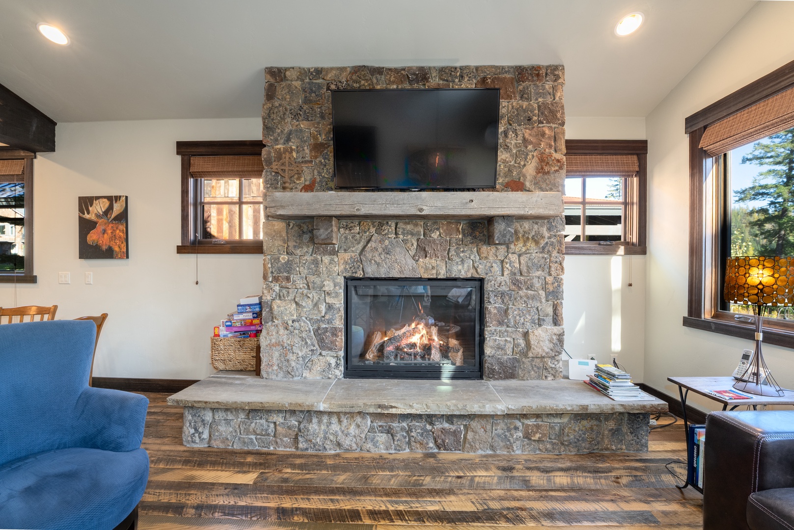 Sink into the cozy blue armchair and feel the warmth of the stone fireplace as you unwind. The rustic timber mantel and mountain-inspired décor set the perfect scene for your alpine escape.