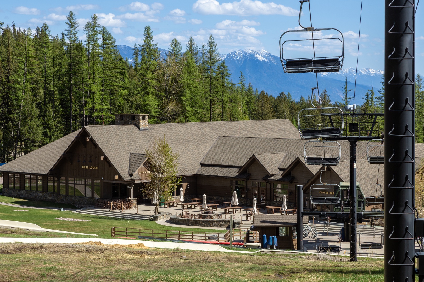 Mountain resort lodge with ski lift access, surrounded by forest and snow-capped peaks, offering immediate access to outdoor recreation and alpine activities.