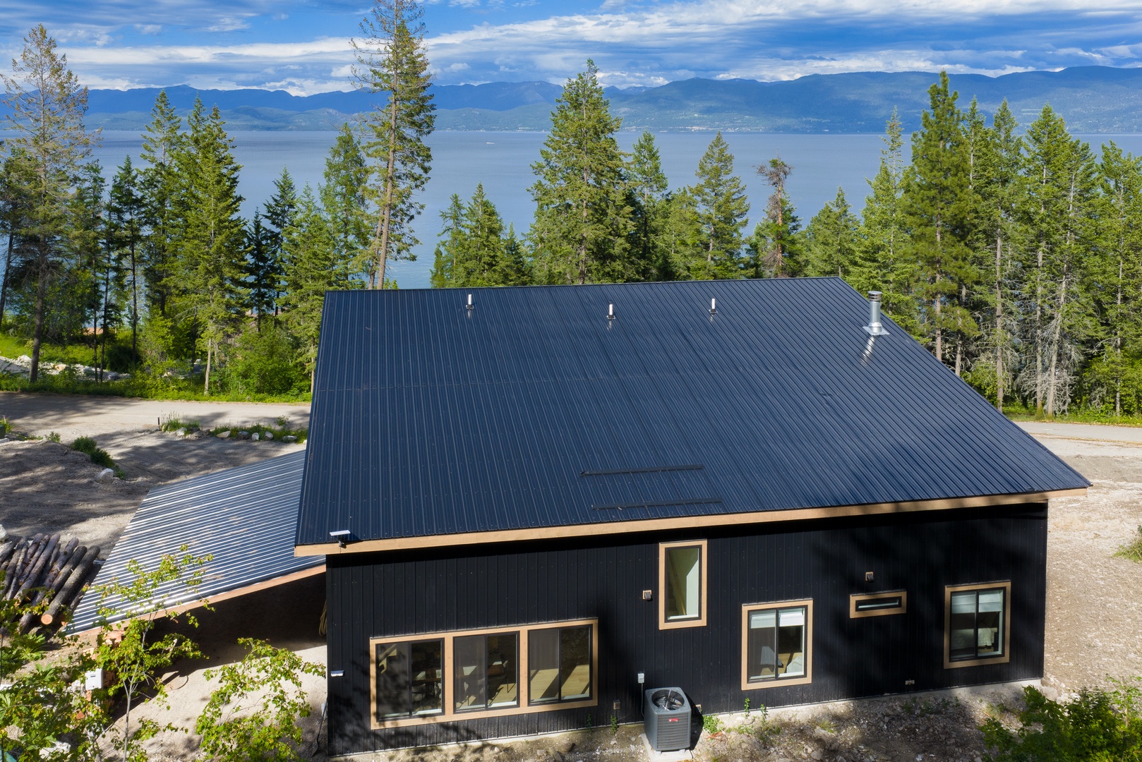 Modern mountain retreat set among tall pines with stunning lake and mountain panoramas stretching across the horizon—a serene location perfect for a peaceful getaway.