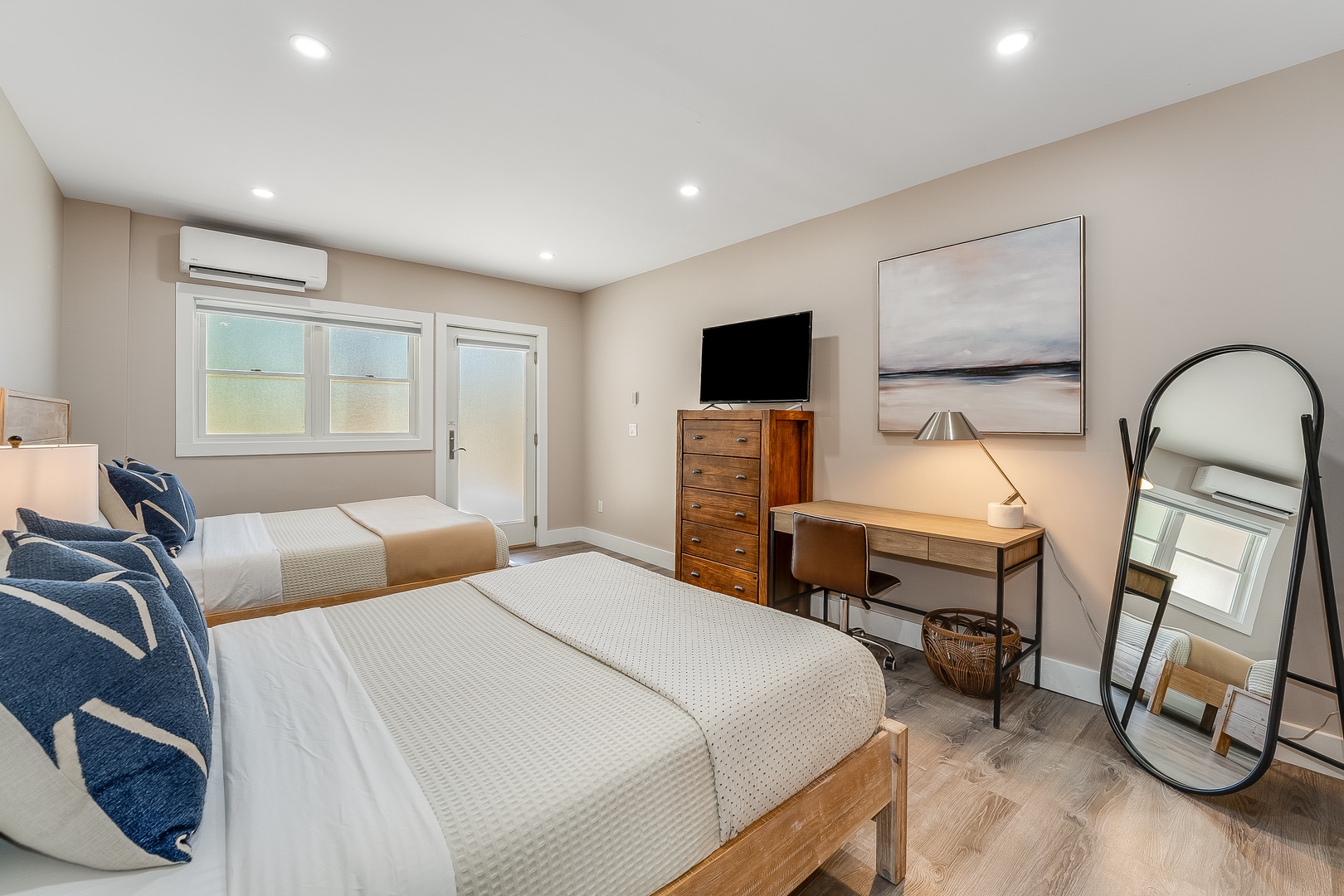 Rest in your bright, airy bedroom with two cozy beds, warm wood accents, and modern conveniences for a truly comfortable stay.