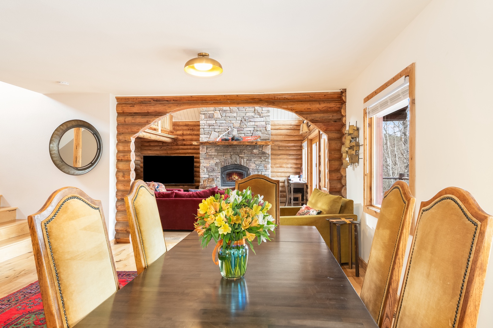 Gather around this elegant dining table while enjoying the warmth of your stone fireplace and panoramic mountain views through oversized windows.